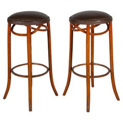 Ensemble de deux tabourets de bar en bois cintré Thonet et assise en cuir rembourrée.