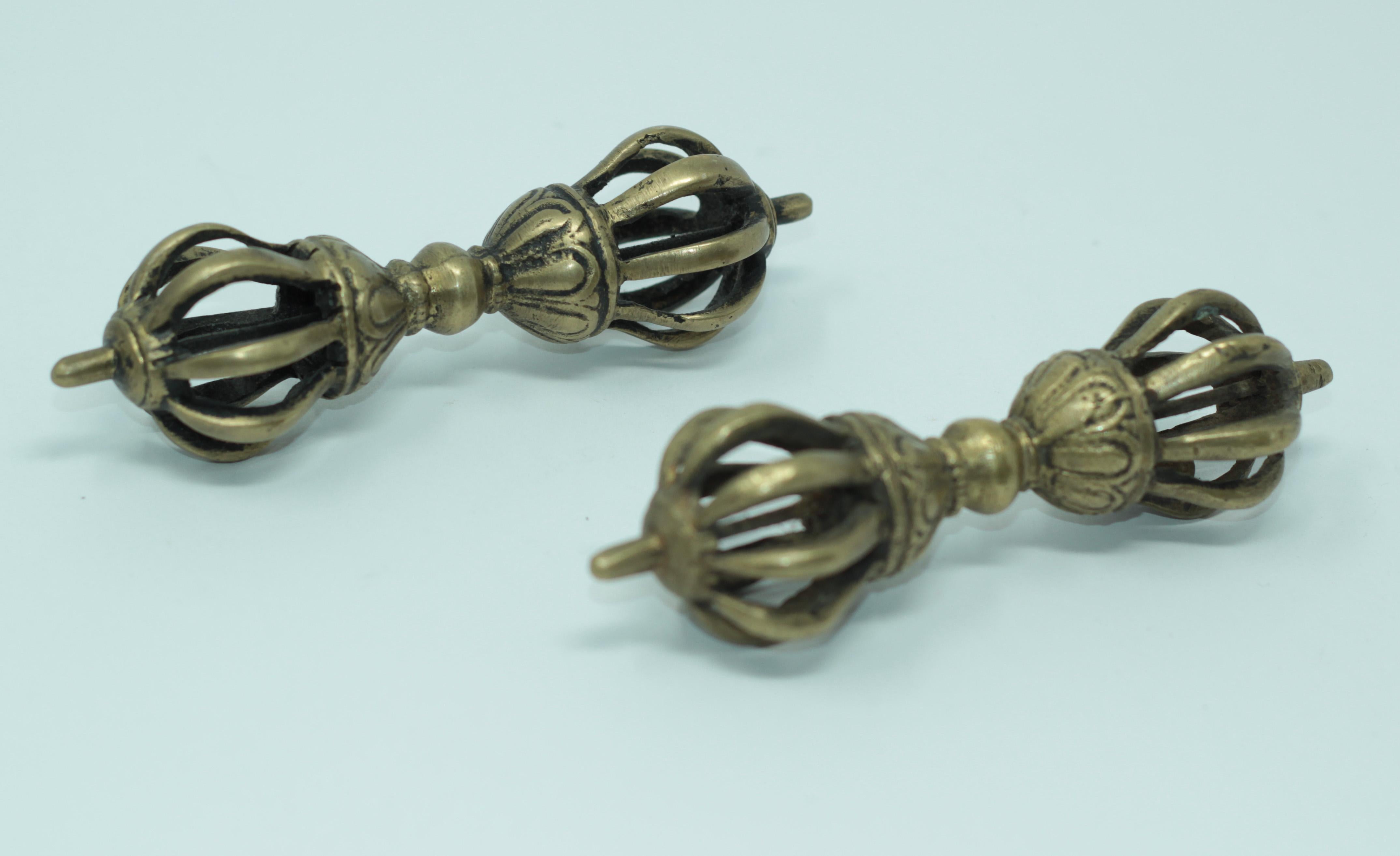 A set of two Tibetan Buddhist gilded cast bronze Vajra.
The gilt bronze Vajra thunderbolt-scepter is cast with a central bulbous grip that separates two lotus pedestals supporting a central column surrounded by eight arched vajra points emerging