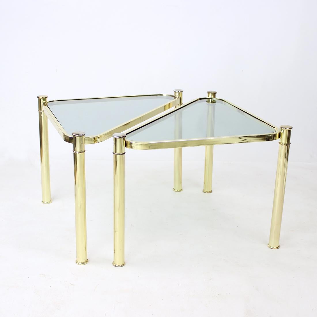 Schönes Set aus zwei Beistelltischen aus Metall mit Messing-Finish und Rauchglas-Platten. Die Tische haben die Form von Dreiecken mit gebogenen Kanten. Die Tische können leicht in verschiedenen Formen aufgestellt werden, sie können zusammen oder