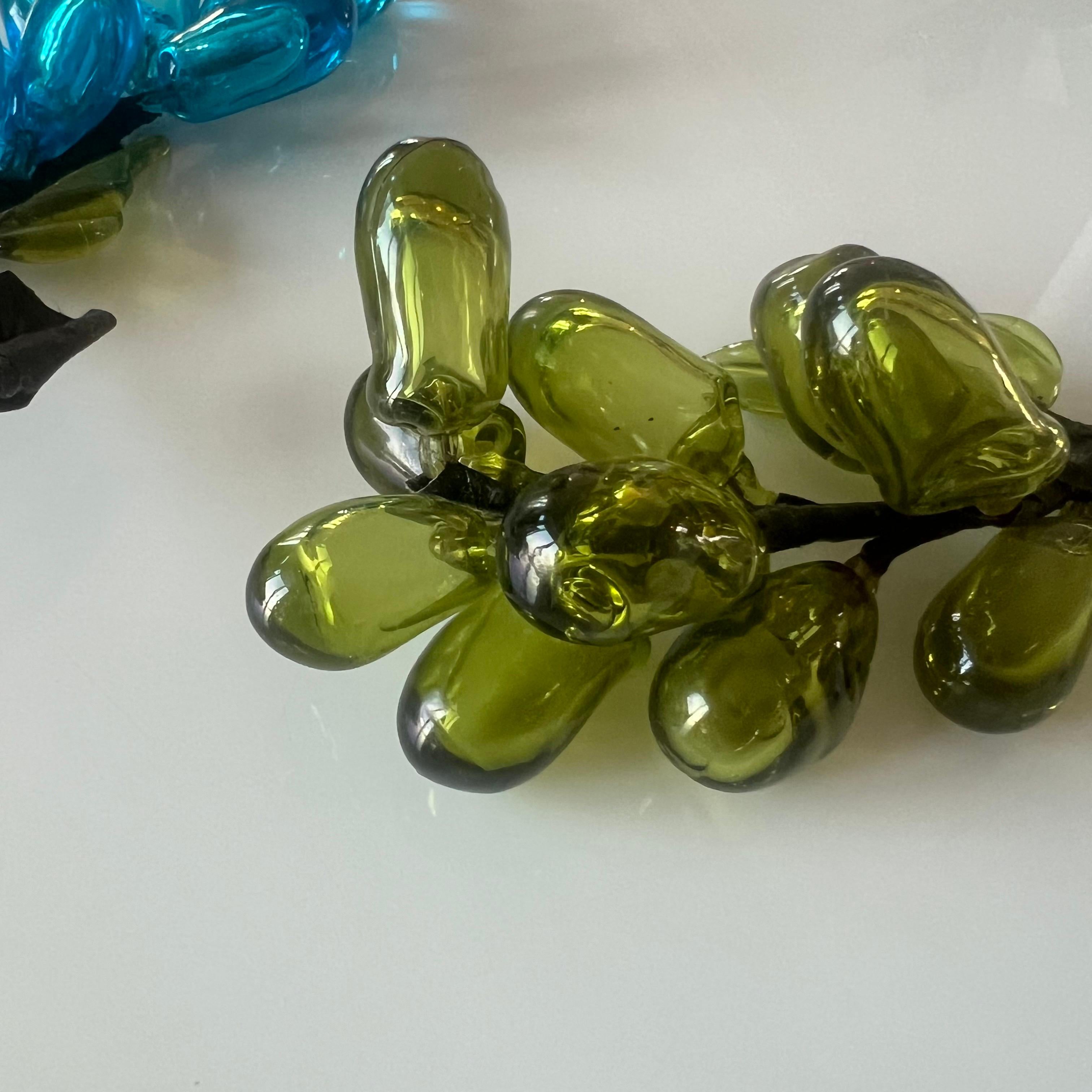 Colorful assortment of blown glass grape clusters: one in turquoise and one in green with nice leaf and vine detail. Elegant decorative objects, ideally displayed loosely on a tabletop or grouped together in a bowl.

Blue measures : 6.75” long x