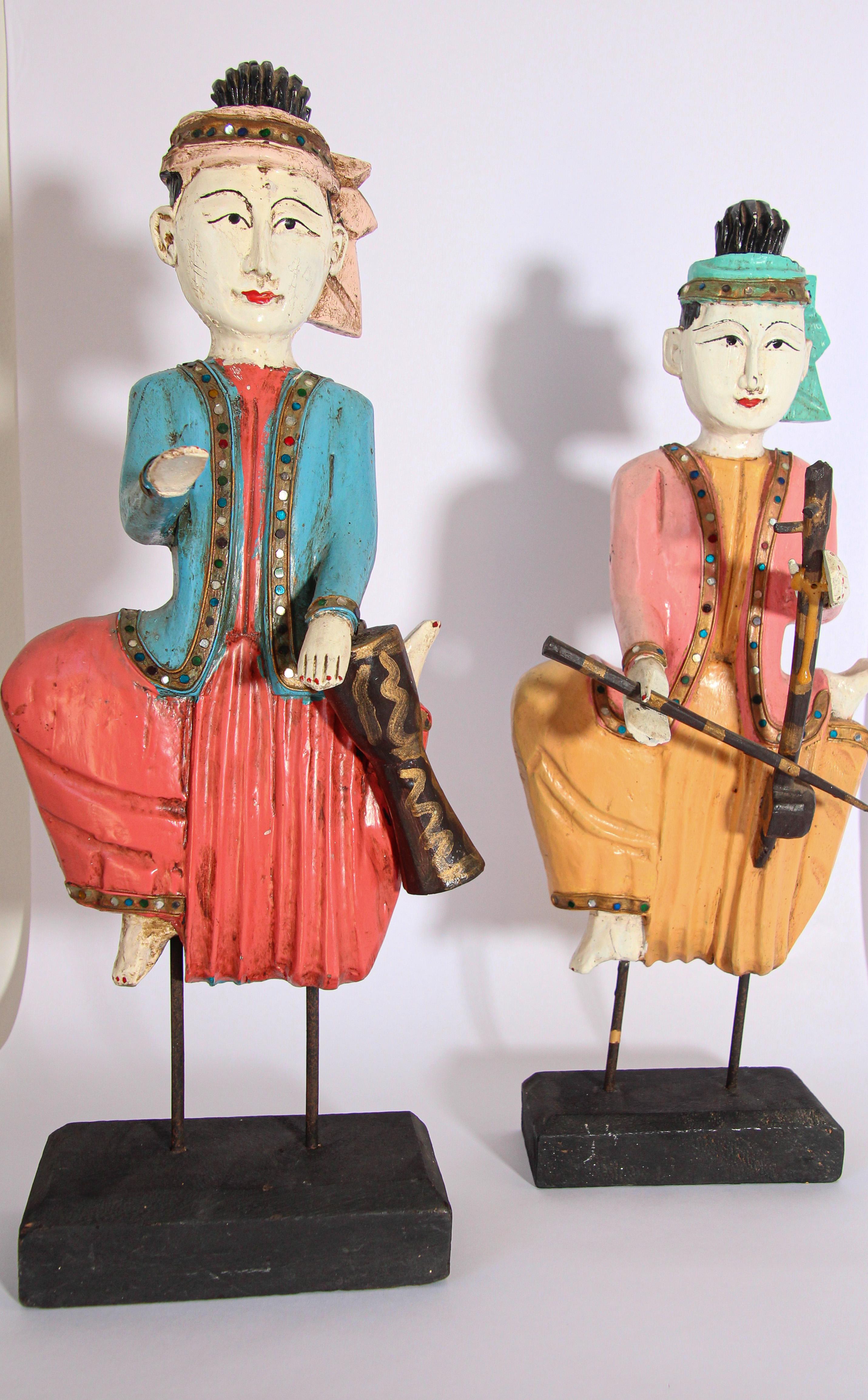 Set of two vintage Thai carved wood colorful sculptures.
Hand carved and hand painted wooden figures depicting traditional Thai musicians. 
The figure sculpture musicians seated are holding a drum and string instrument.
Thai musicians, portrayed