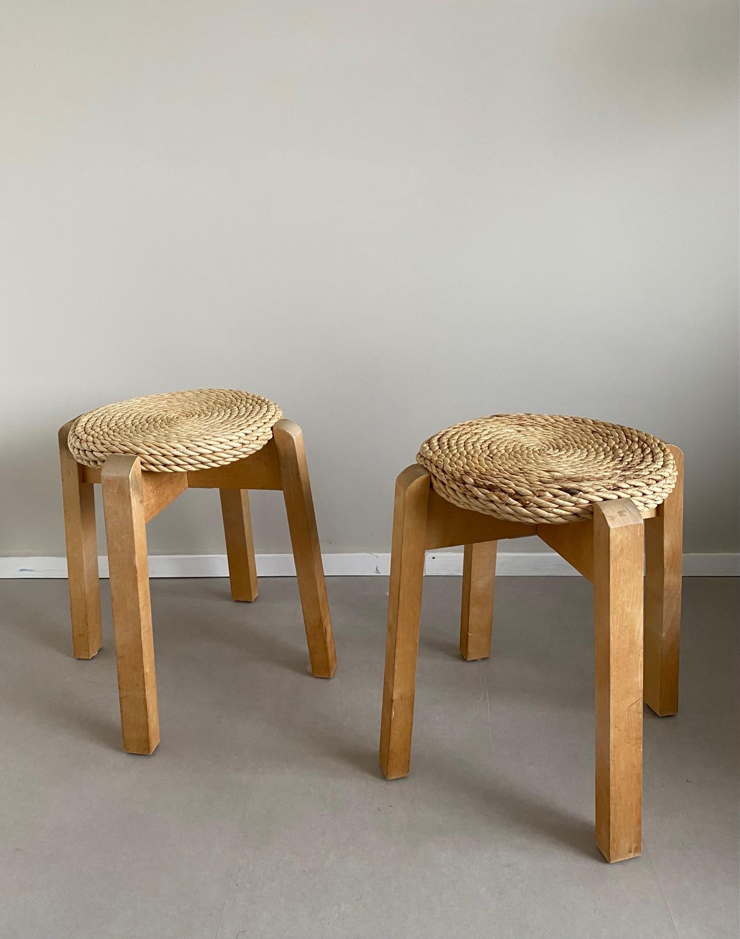 Set of Two Wonderful Woven Stools in Style of Adoux And Minet, Manufactured ca. the 1970s. Stools Feature a Woven Seating with An Organic Rope. Their Wooden Base show some wear as Stains and Scratches As To Be Seen On The Images. Scandinavian Look.