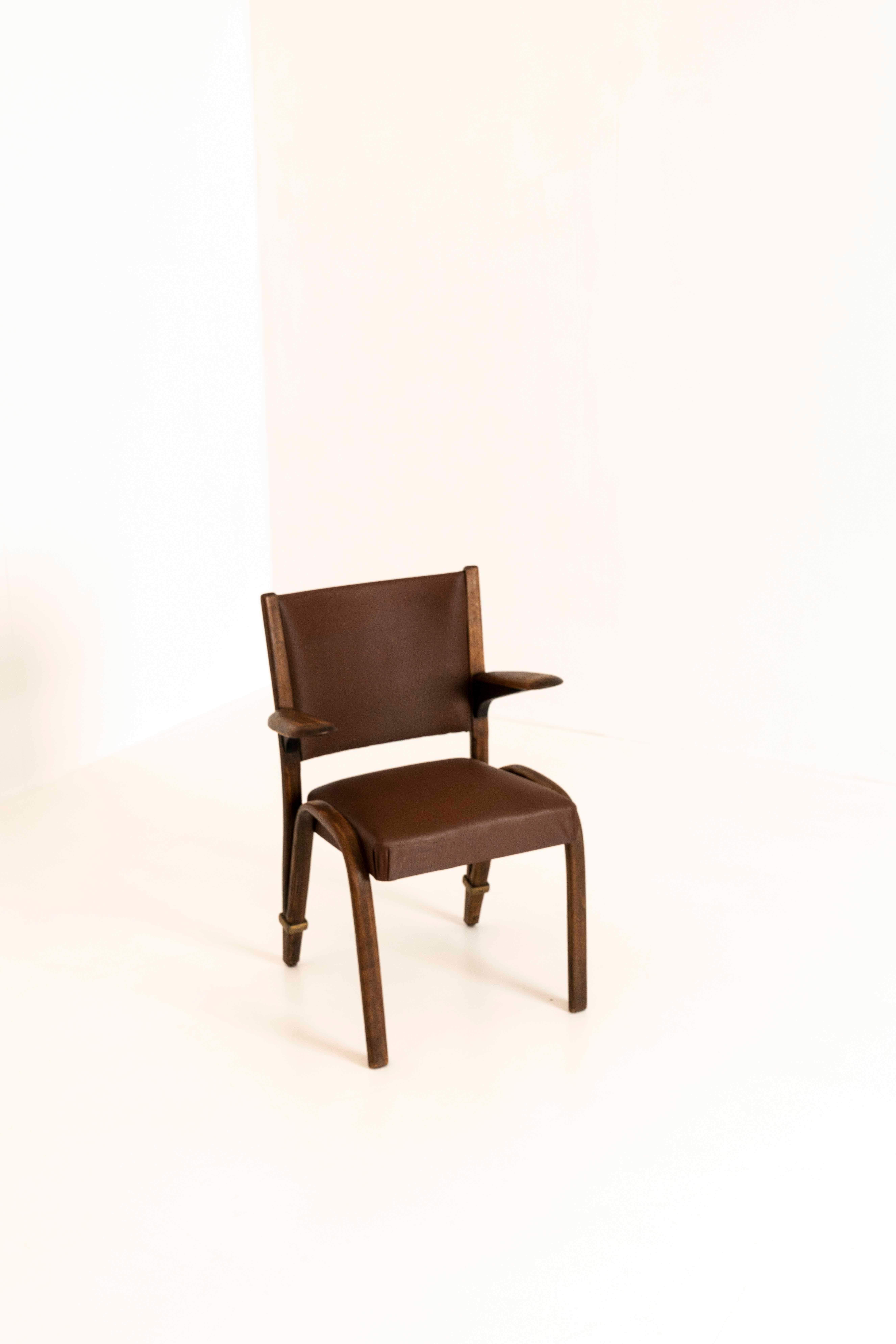 Set of two vintage French chairs by Hugues Steiner from the 1960s. These 'spring back' chairs have a very exceptional design that is recognizable for Hugues Steiner. They have a dark brown 'skai-like' cover and a dark-brown wooden base. They are in
