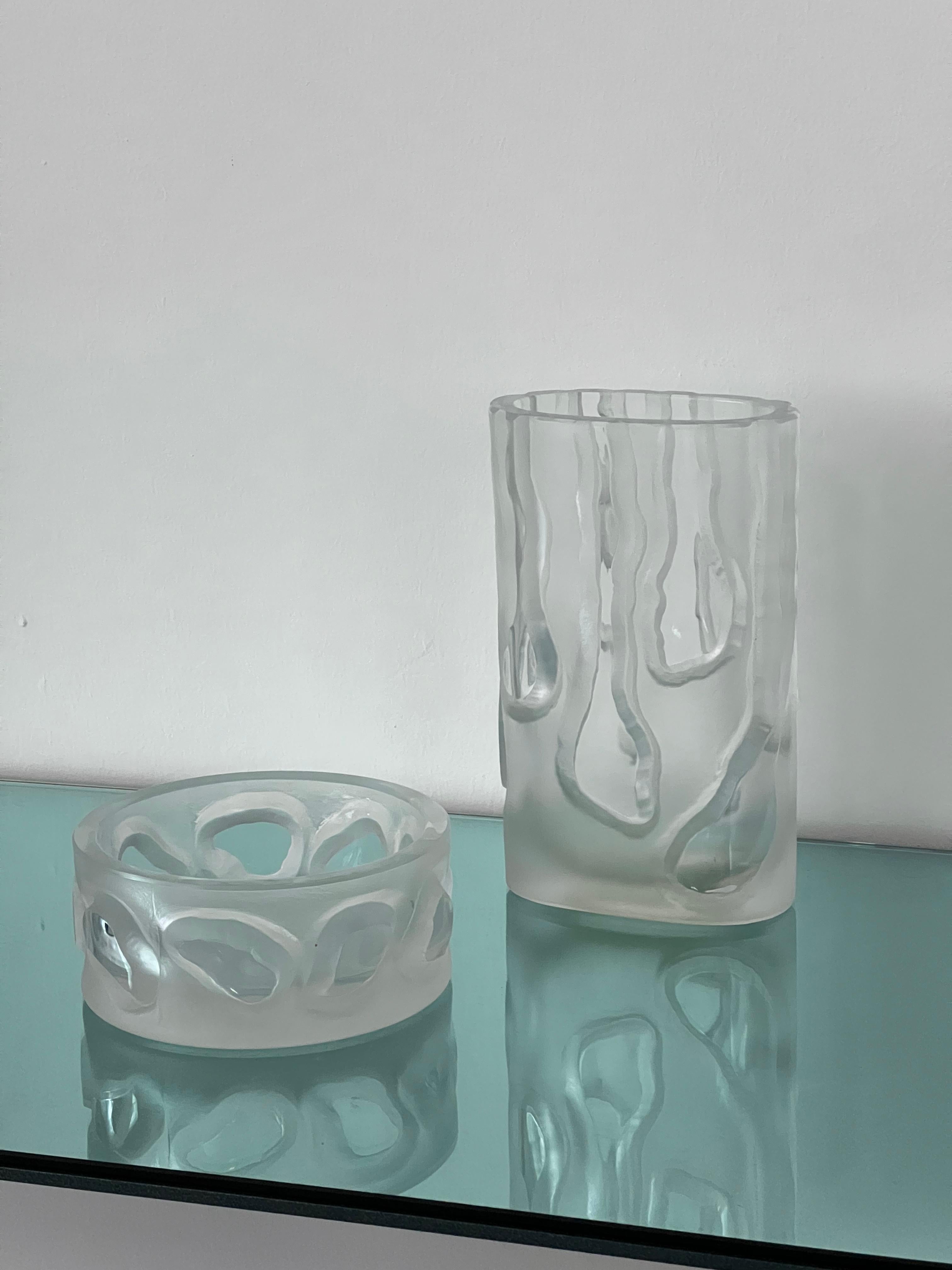 Vintage set of two matching glass pieces, a tall vase and a low bowl, both made in the same shade of clear glass and both with a frosted/sandblasted surface and egraved decorations that bring out the smooth surface of the glass. They are designed in