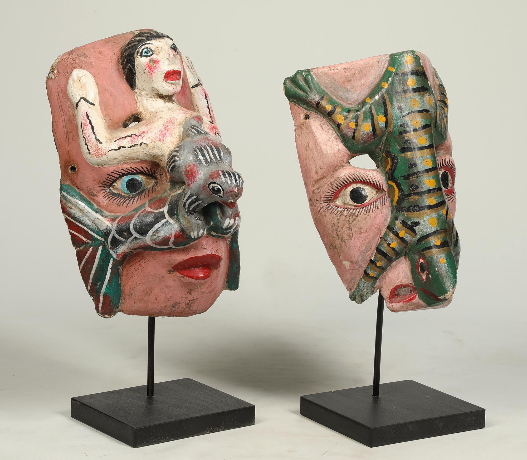 Group of two polychrome painted wood mid-20th century Mexican dance masks.  Each with a face one with a lizard on top and the other with a mermaid.  Some chips, wear and darkening of inside.
Mermaid mask is 10.5 inches high, on custom wood base,
