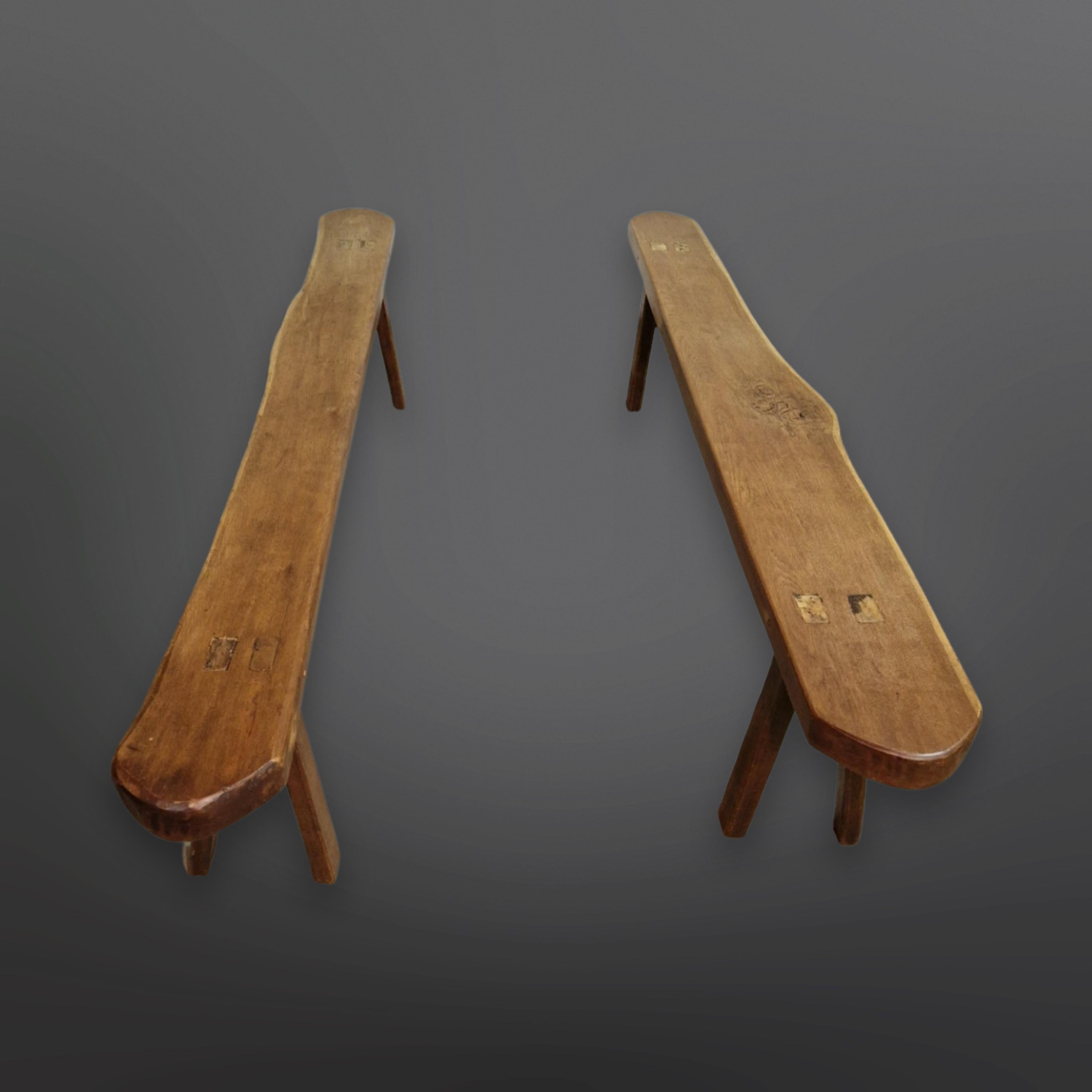 Set of two rustic wabi sabi benches. They are made from solid oak. The seats are made from a single piece of wood. The legs have been fitted through the wood. They are different in size and shape due to the natural characteristics of the wood. Both
