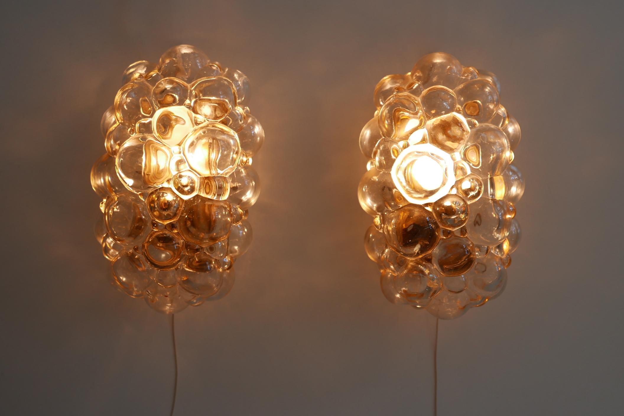 Amazing set of two Mid-Century Modern wall lamps or sconces. Designed by Helena Tynell for Glashütte Limburg, 1950s, Germany.

Executed in amber-colored bubble glass and brass sheet, each lamp comes with 1 x E14 Edison screw fit bulb holder, is