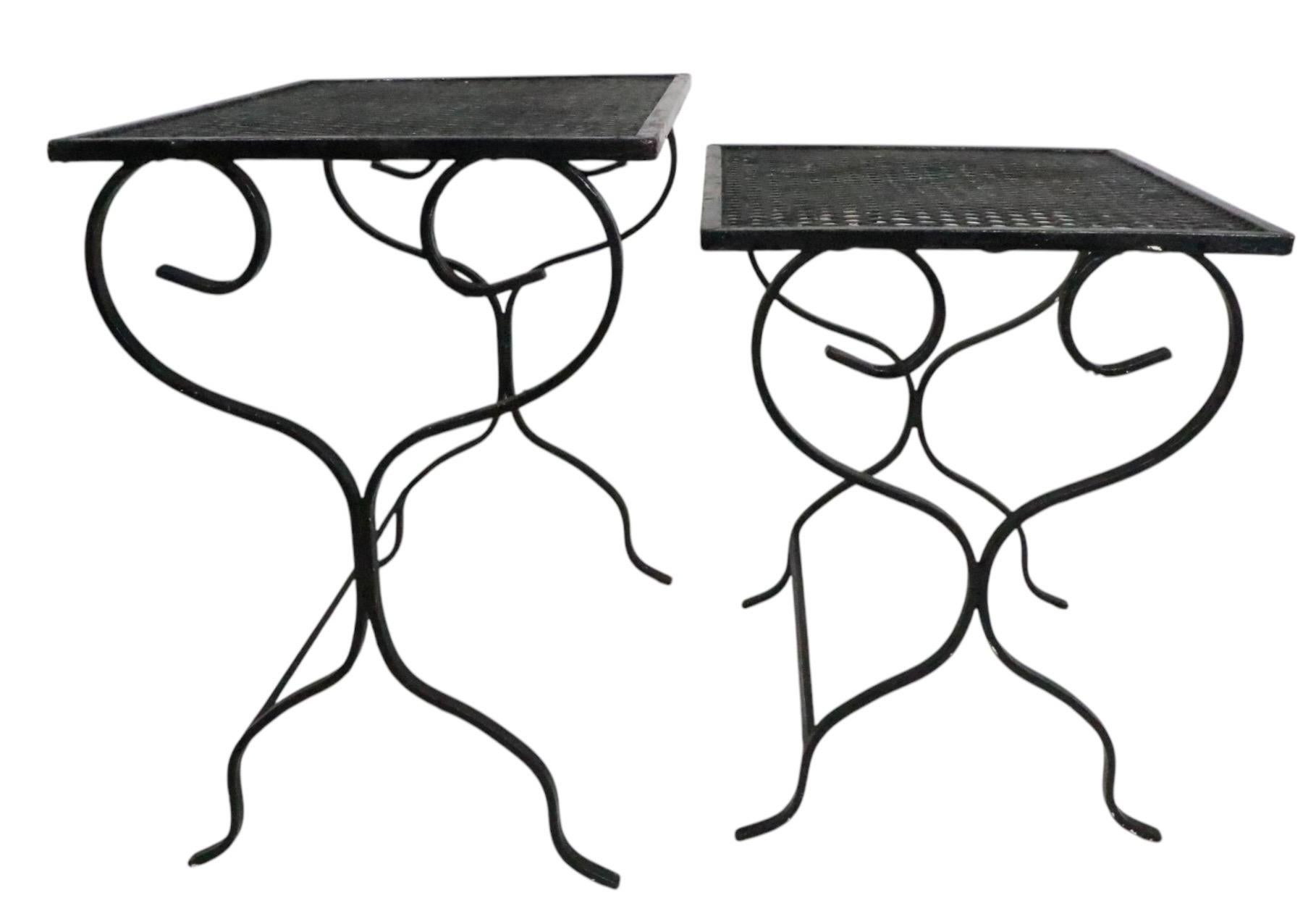 Juego de dos de mediados de siglo  Mesas nido de hierro forjado y malla metálica, atribuidas a Woodard Furniture circa 1950/60's. Ambas mesas son estructuralmente sólidas y robustas, ambas presentan desgaste cosmético en el acabado de la pintura,