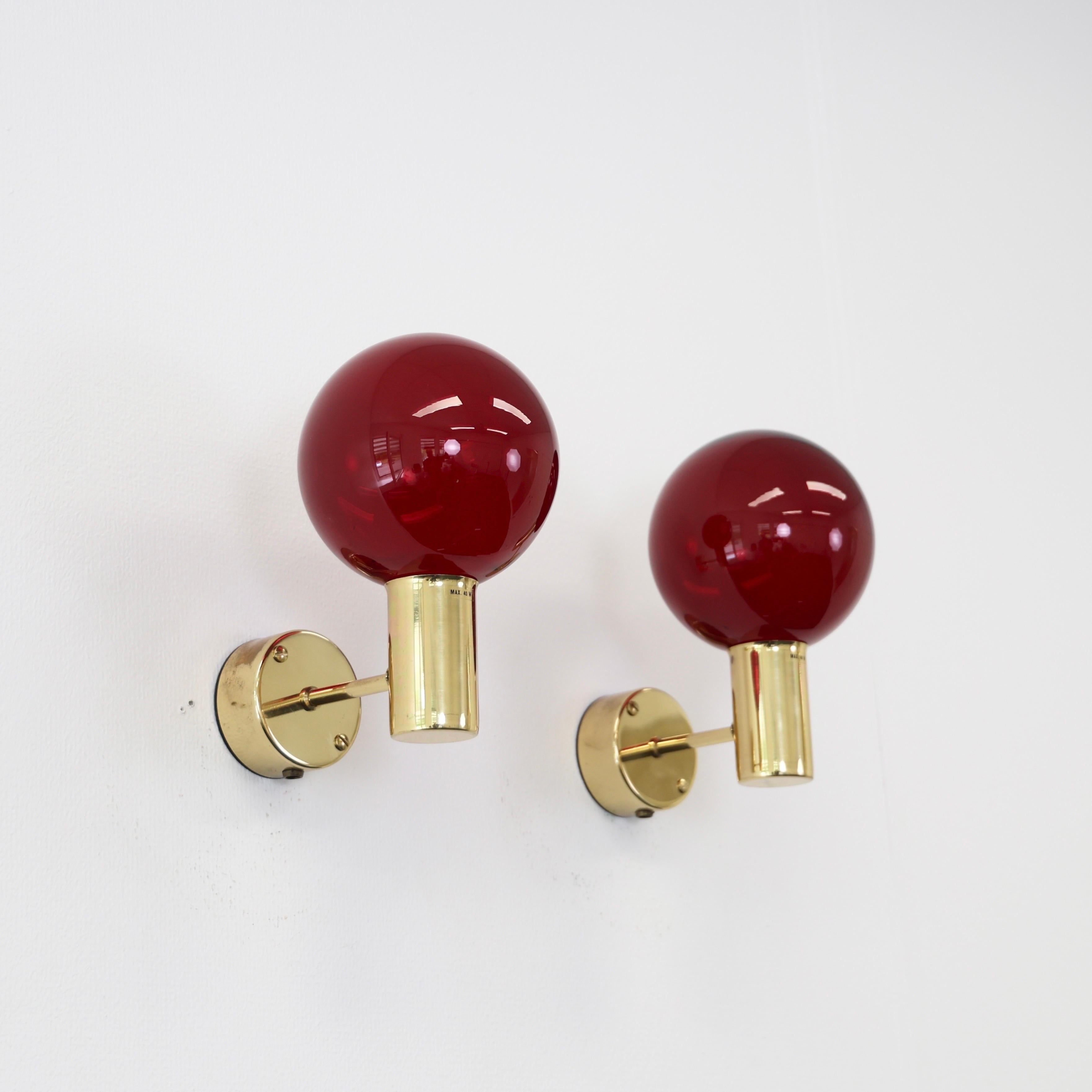 Conjunto de apliques modernos suecos de latón con pantallas de cristal rojo intenso, diseñados por Hans-Agne Jakobsson en la década de 1960. 

* Pareja (2) de apliques de latón con tulipas de cristal rojo intenso
* Diseñador: Hans-Agne Jakobsson
*