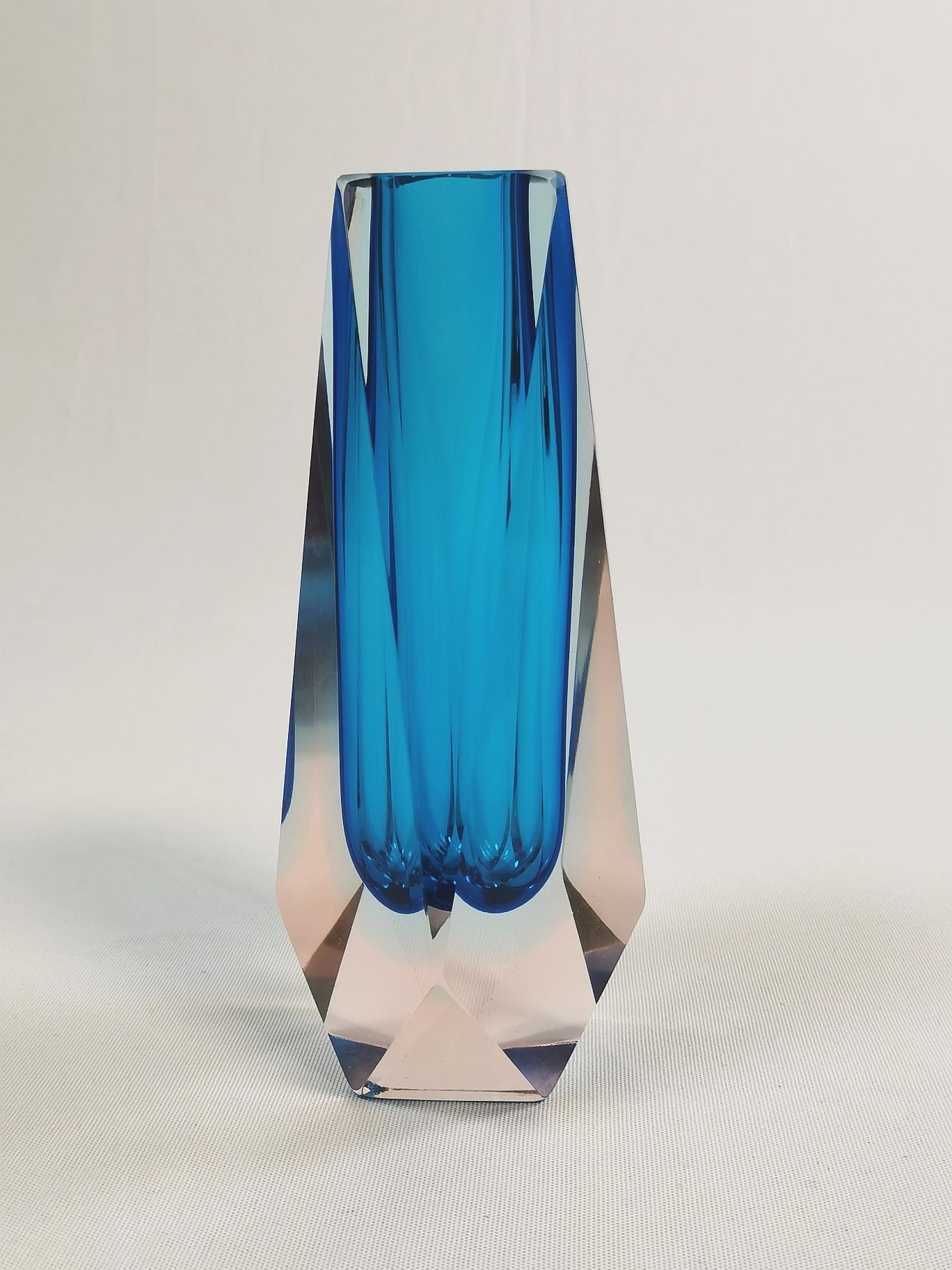 Questo particolarissimo insieme di vaso e posacenere con spintore proviene da Murano, in Italia.
In base al taglio sfaccettato corrispondente e alla sfumatura di colore, è quasi certamente della casa di Mandruzzato. Un'azienda familiare gestita da