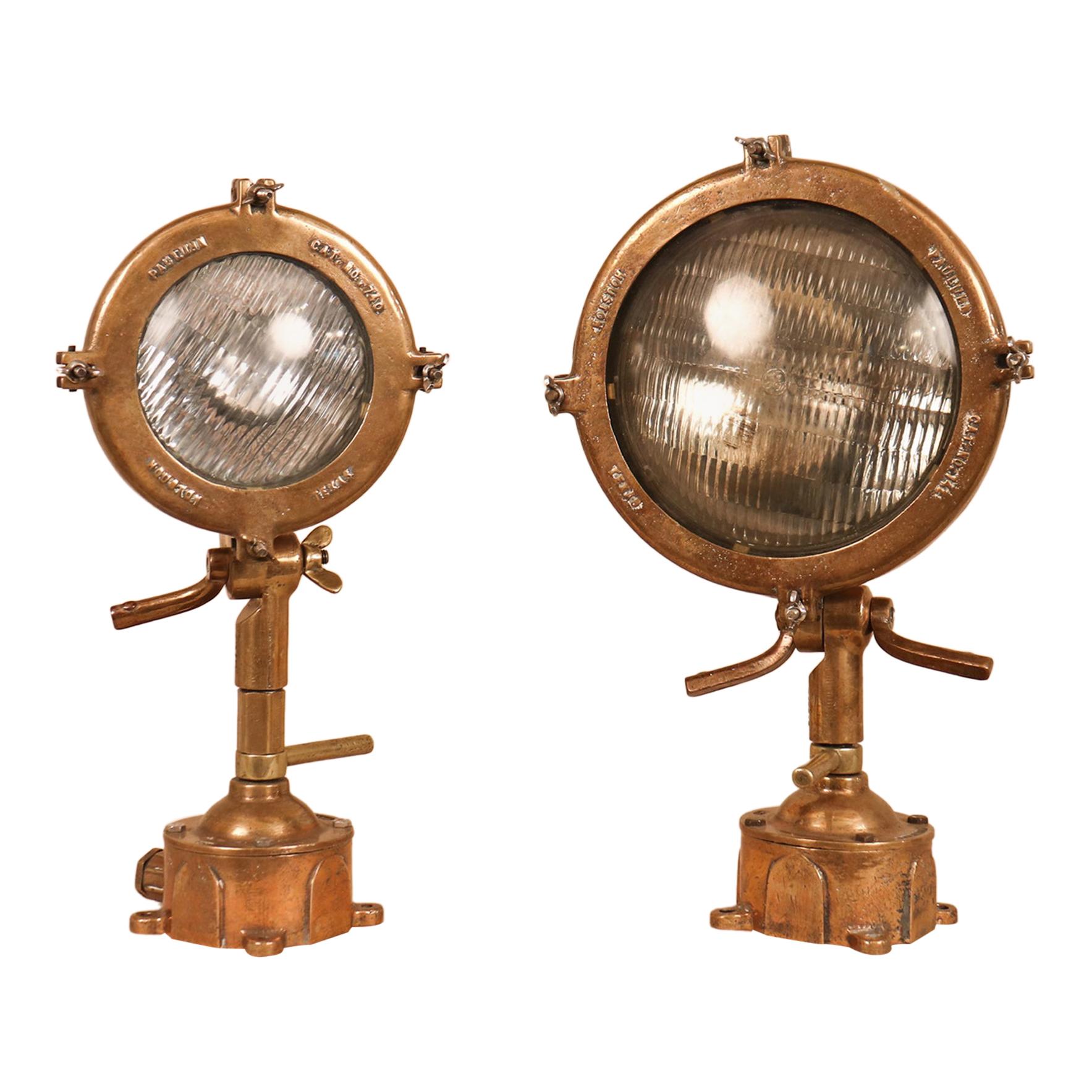 A set of 1960s solid brass maritime spotlights manufactured by Eaton Crouse-Hinds, Houston, TX. These Pauluhn big and little sister lanterns (series 740 and 742) feature adjustable, incandescent lamps and heat resistant glass. The lights come
