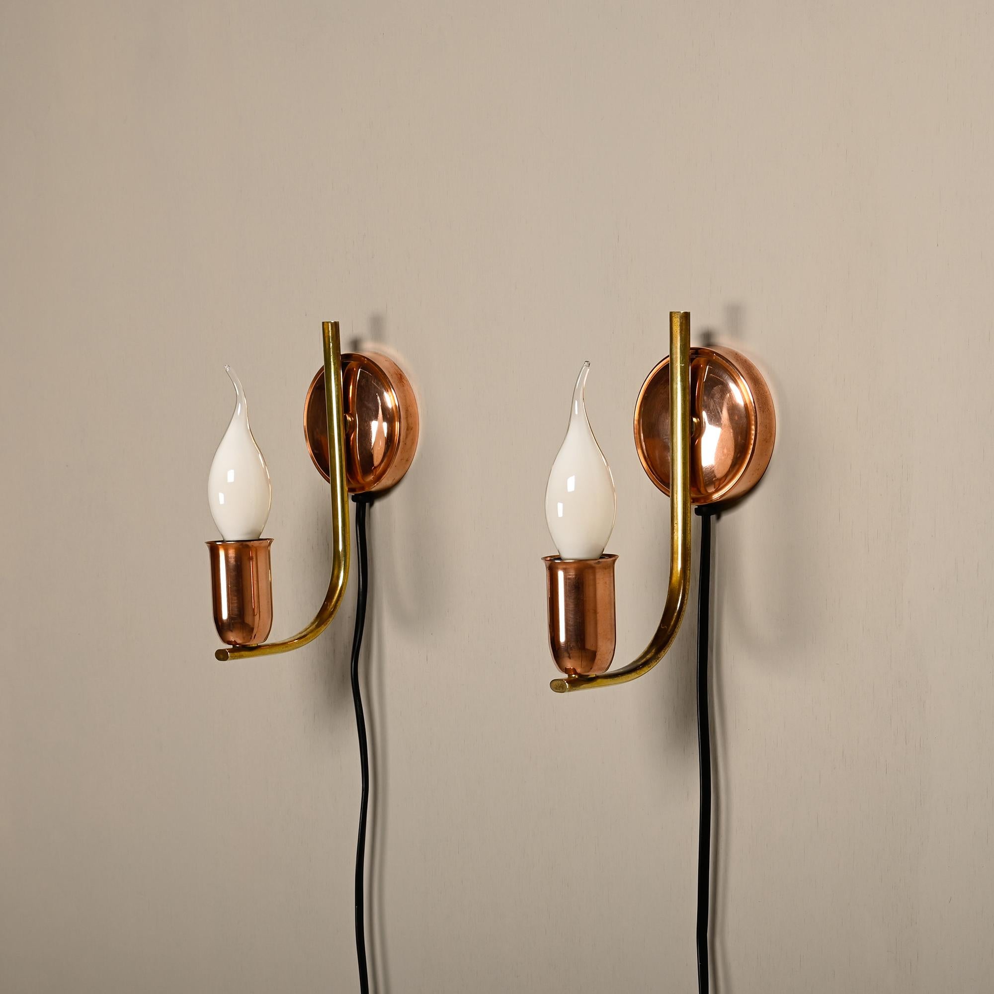 A beautiful pair of vintage wall lamps produced in Denmark in the 1950s. Copper bases and lamp holders are connected by an elegantly curved brass connection. In very good condition, the metal parts have been polished and the lamps rewired. The lamps