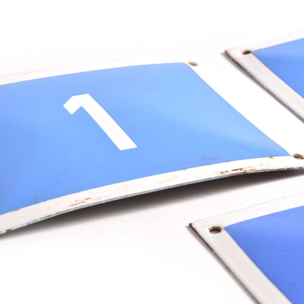 Un ensemble remarquable de neuf plaques de numéros en émail vintage provenant de Tchécoslovaquie, vers les années 1950. Chaque plaque présente un chiffre blanc (de 1 à 9) sur un riche fond bleu cobalt, encadré d'une bordure blanche classique.