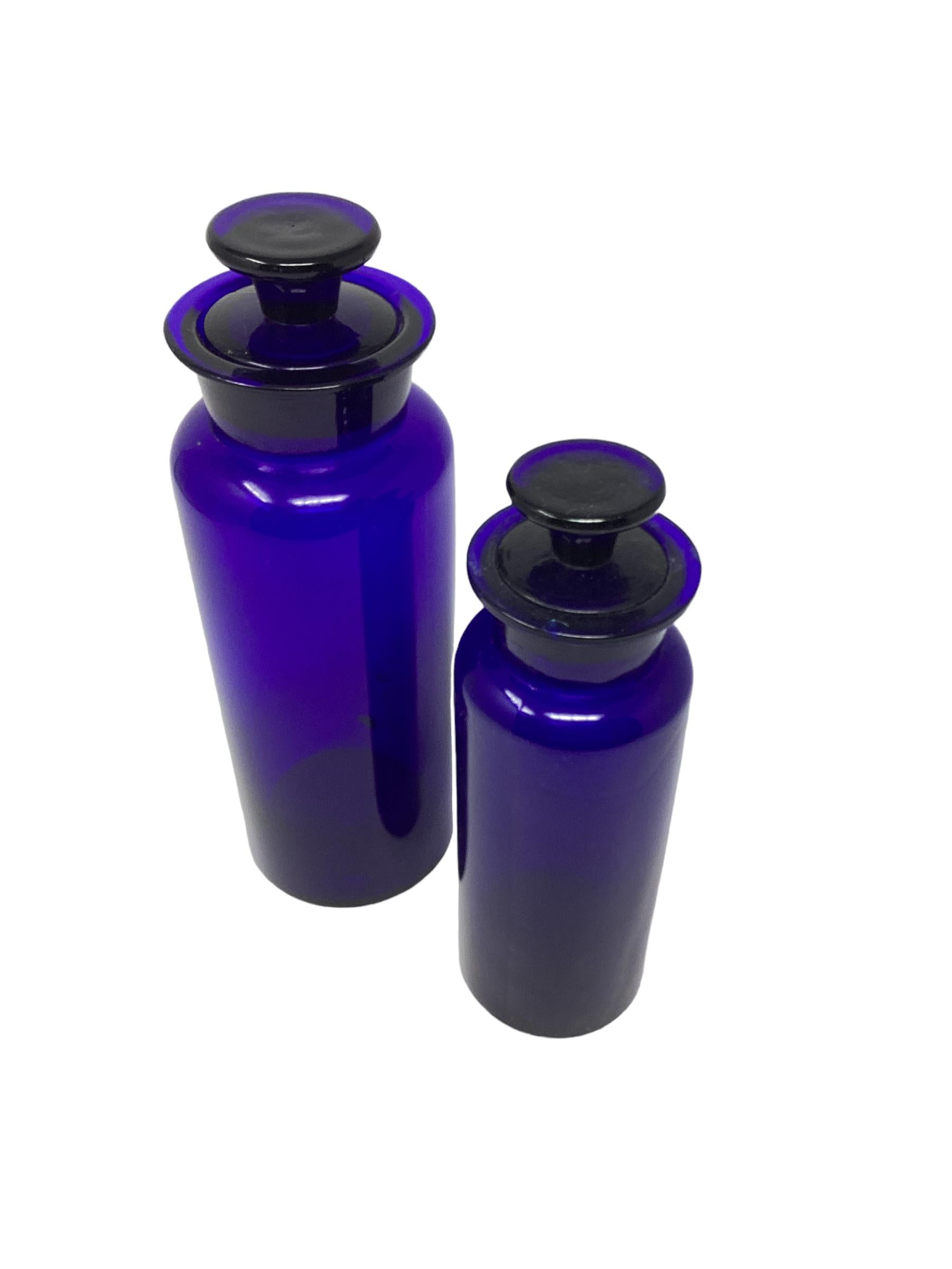 Set of Vintage Cylindrical English Cobalt Blue Apothecary Jars . The bigger one measures 10” x 3.5” and the smaller one is 8.5” x 2.75. Both stoppers are stuck and do not come out.