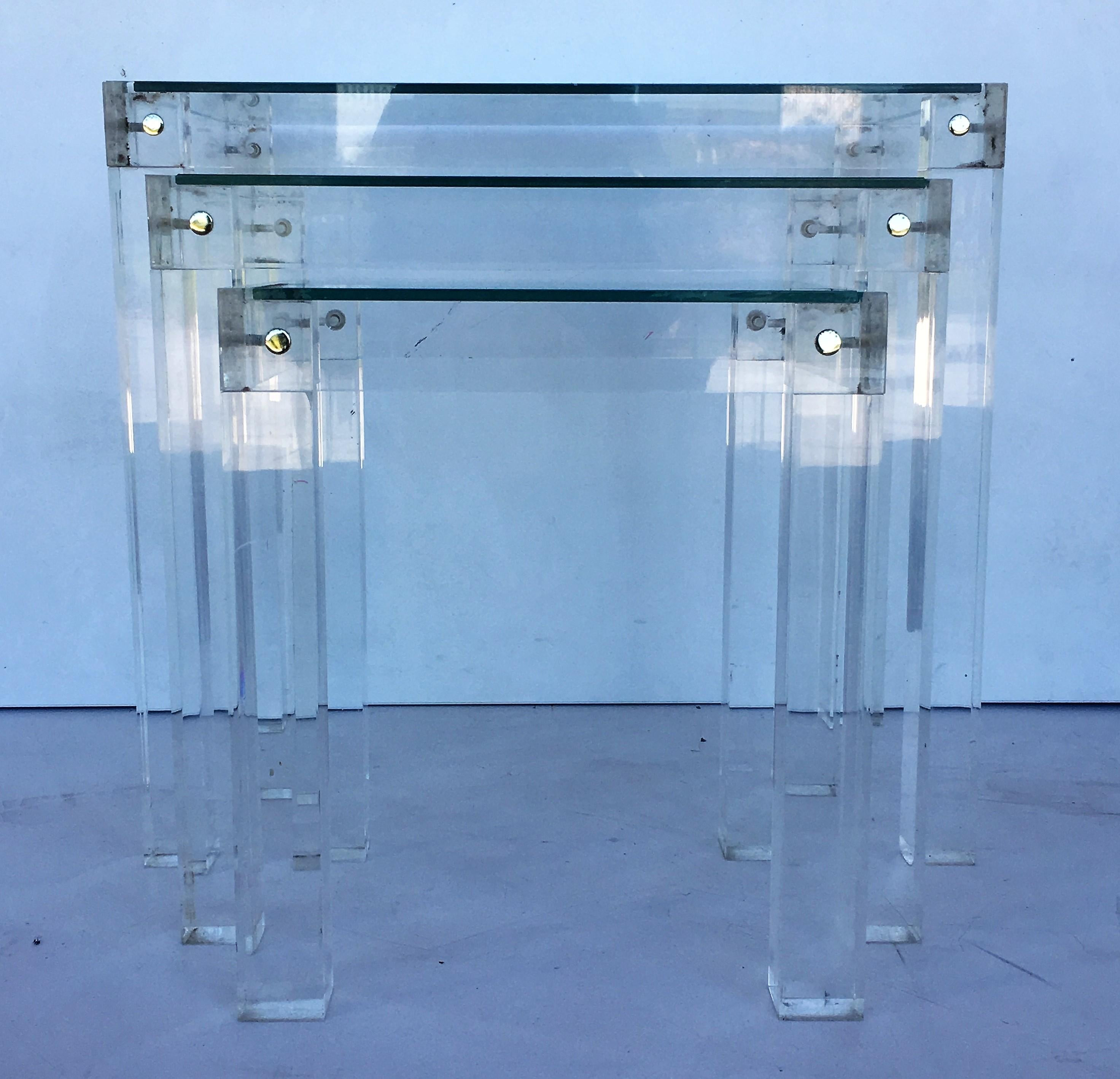 These Mid-Century Modern nesting tables embody the 1970s. They are comprised of a Lucite frame joined by connectors and a glass top. 

Please note the Lucite is clear, the blue hue is from the background wall paint in the showroom.

Measures: