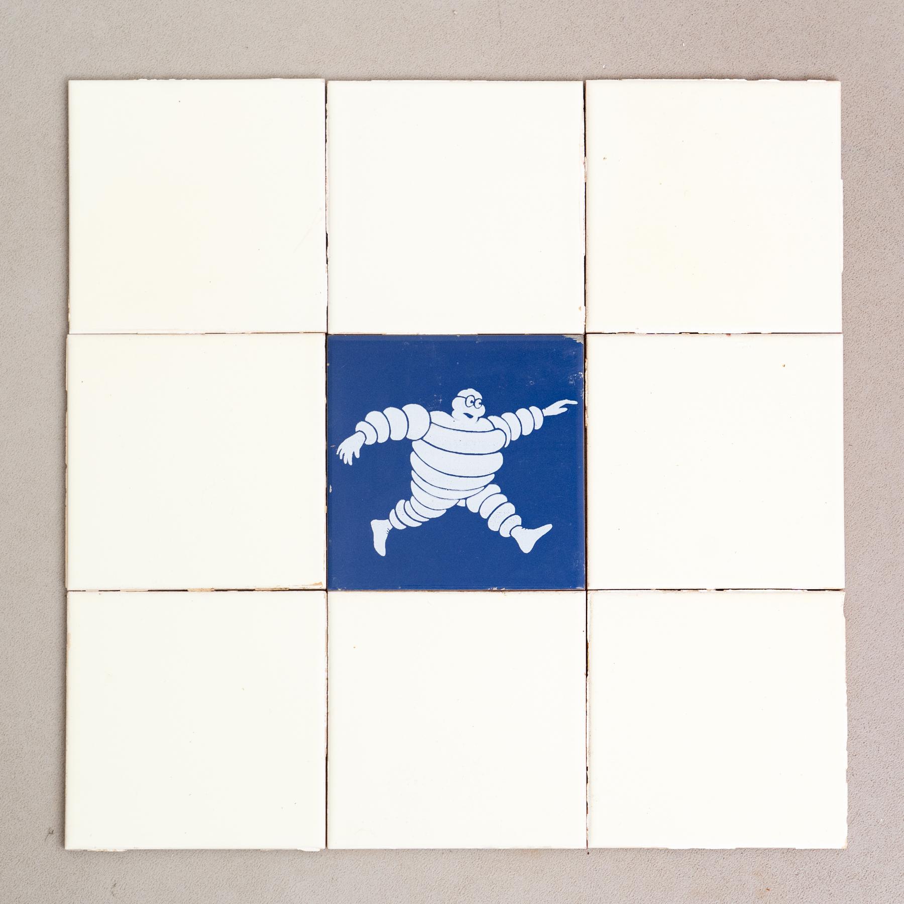 Embark on a journey of vintage charm with this exceptional set of tiles, featuring the iconic Michelin Man in a vibrant blue centerpiece, surrounded by original yellow tiles. Crafted by an unknown manufacturer in Spain circa 1960, this set is a