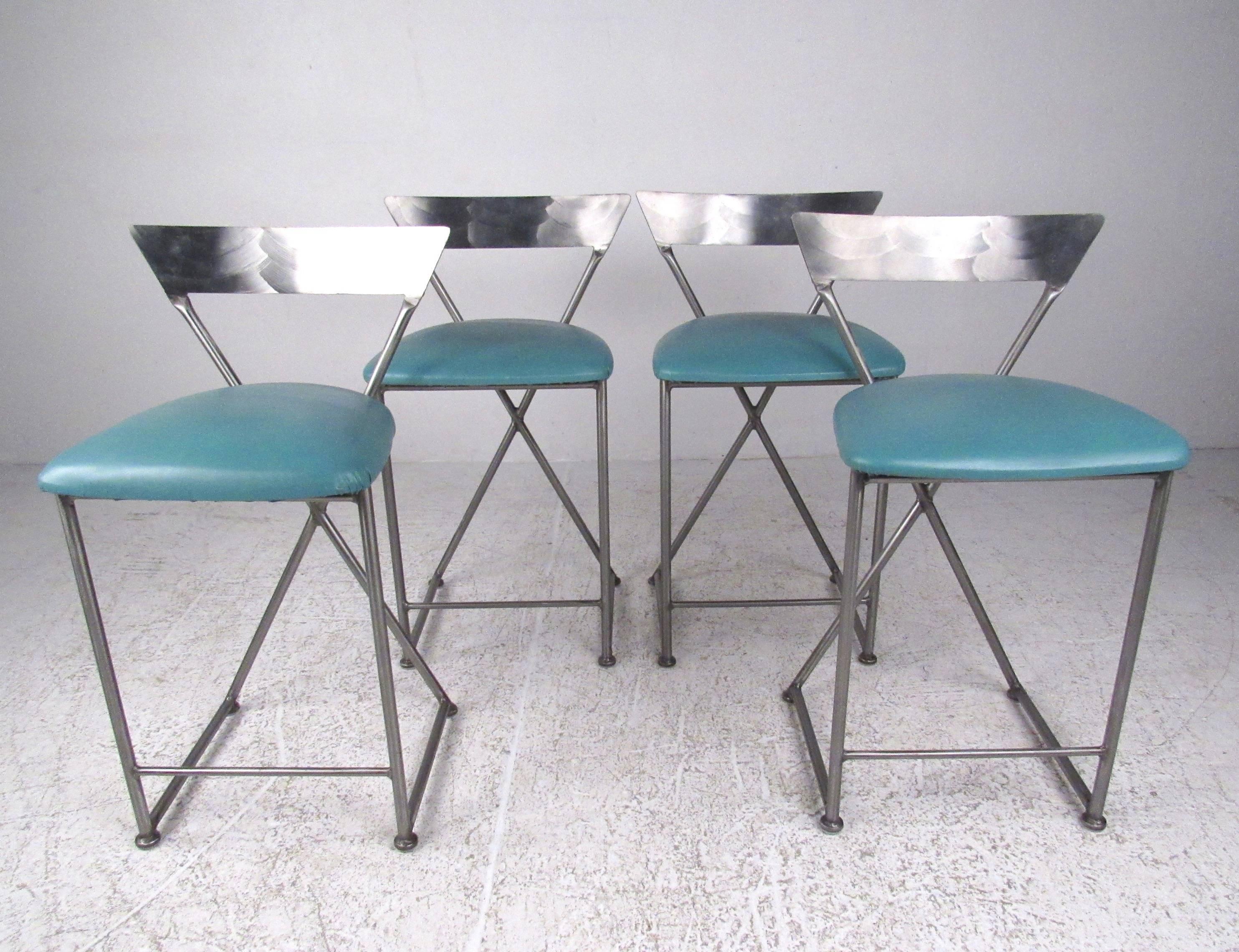 This stylish set of vintage modern bar stools by Shaver-Howard feature teal vinyl upholstery and shapely seat design. Textured stainless steel finish adds midcentury industrial flare to home or office counter seating. This impressive matching set of