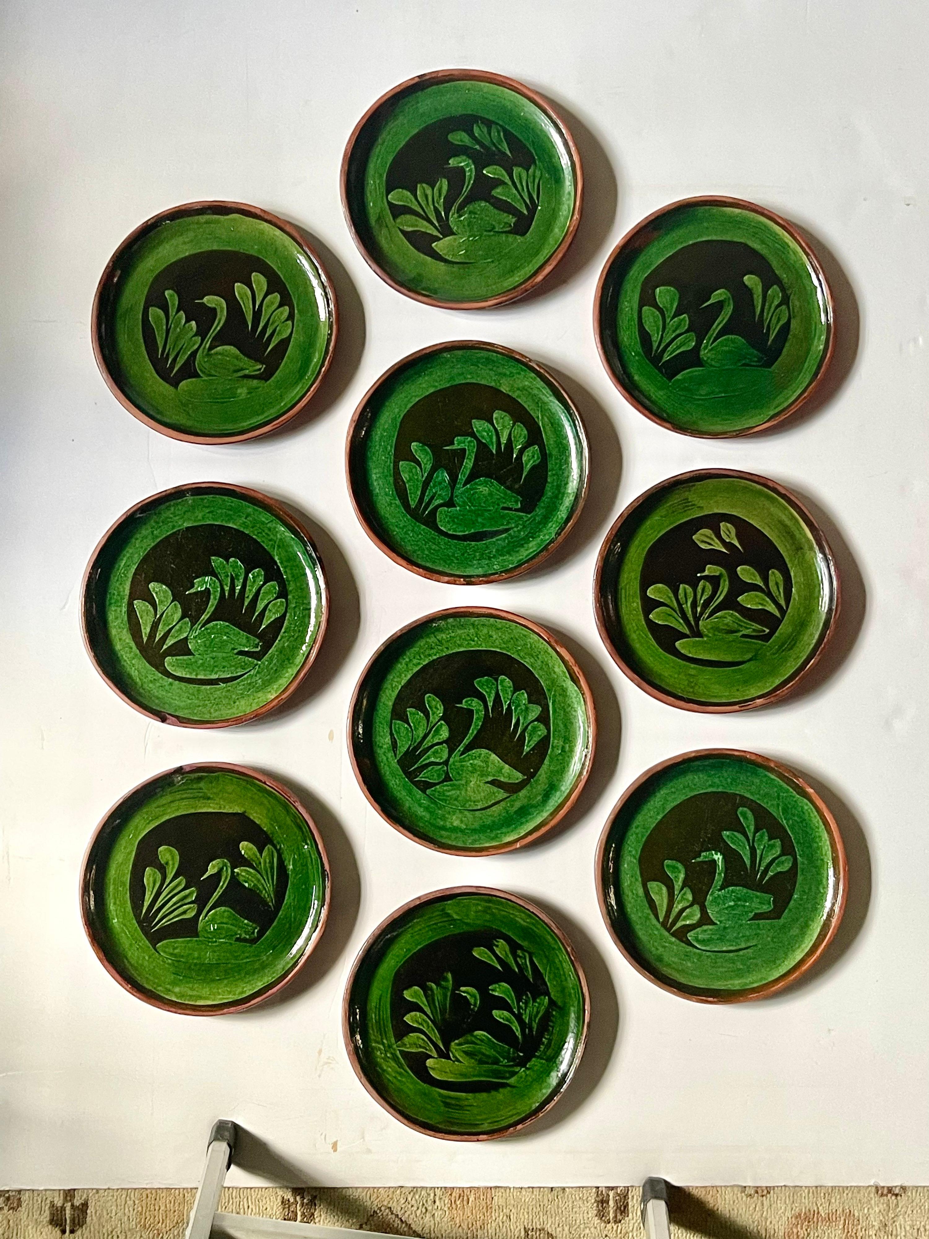 Beautiful vintage set of Patamban decorative pottery plates made by folk artists in Michoacán, Mexico. The round plates feature a rich green glazing on the front with swan designs in an off-black relief. Perfect for cabinet display or a plate wall!