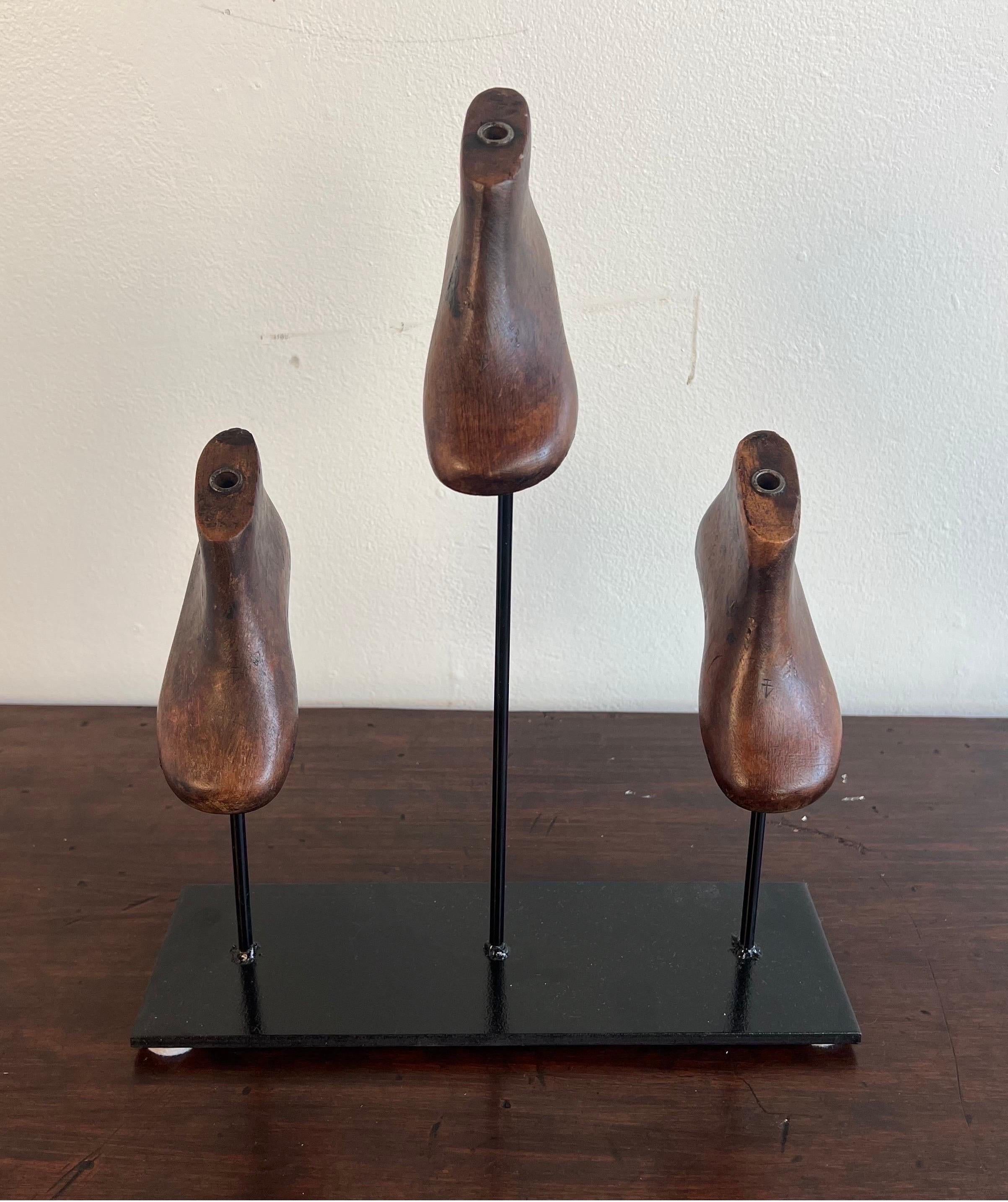 Set of three wooden child size shoe forms mounted on an iron base.