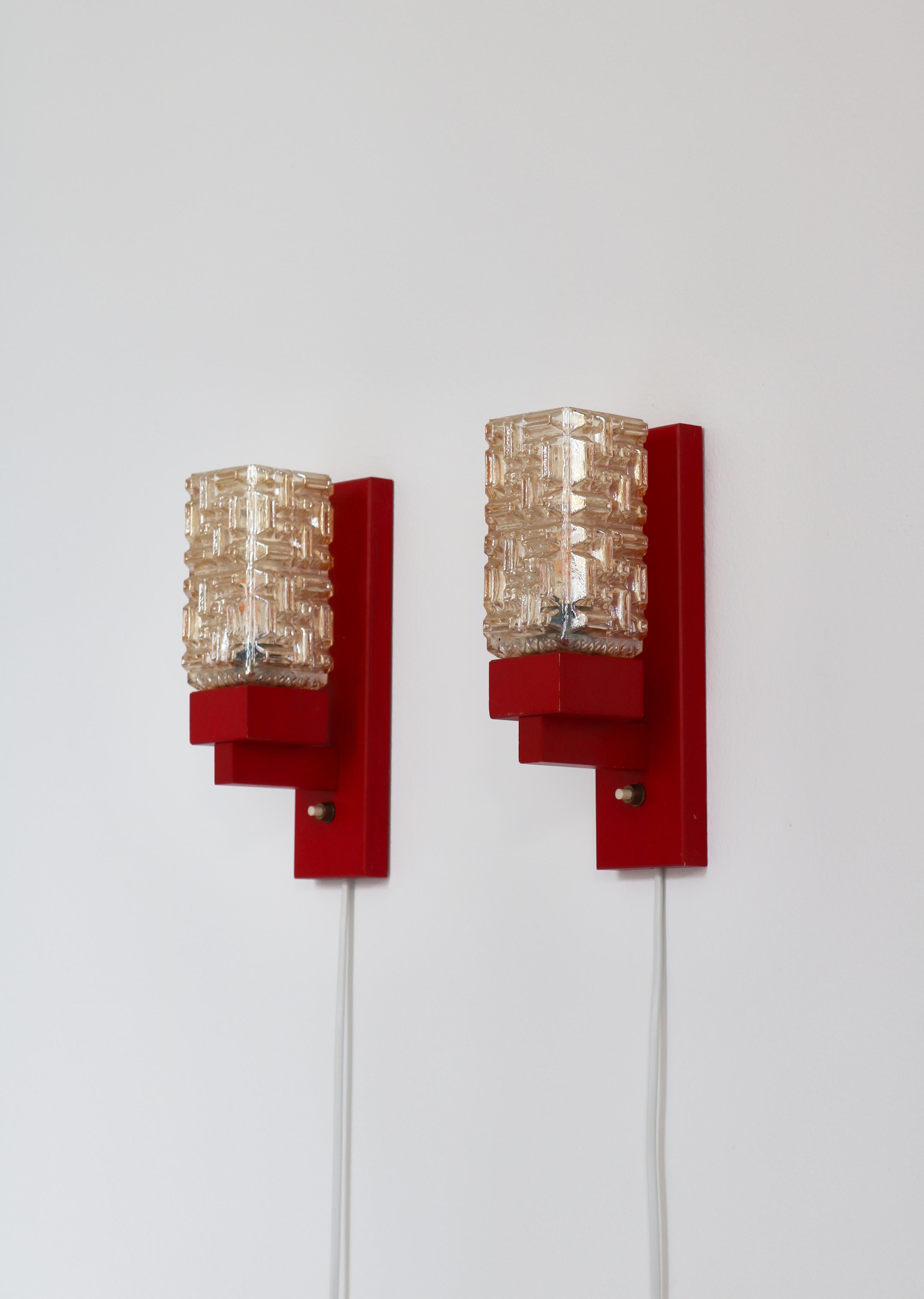 Wonderful set of Danish Modern wall lamps in red lacquered wood and amber colored glass shades. The lamps were made in the 1970s by the small Danish workshop 