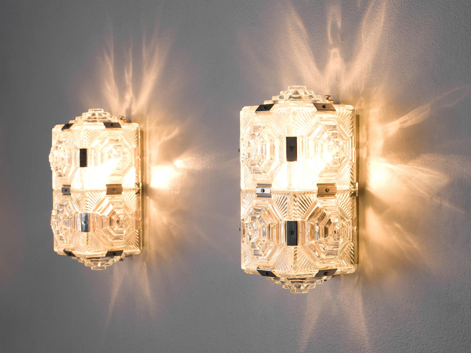 Set of wall lights, brass, structured glass, Europe, 1950s

These stunning wall lights consist out of eight glass parts each that form a rectangular lamp with five sides. Visible brass connections held the design together. Each glass is structured