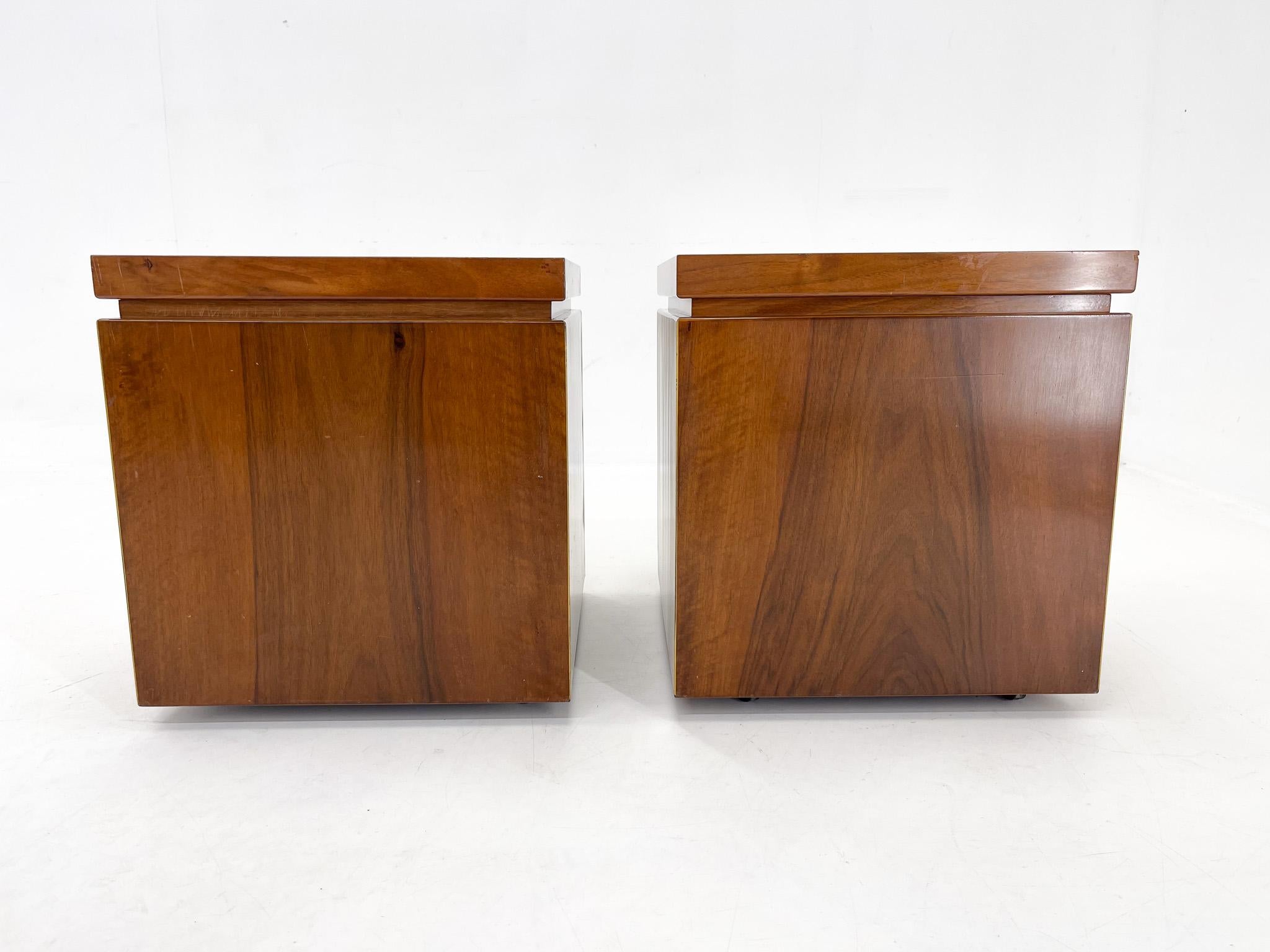 A pair of beautiful vintage bedside tables made in Italy in the 1950s. The tables have castors and can be easily stacked. They are made of high gloss walnut veneer with brass and golden details.