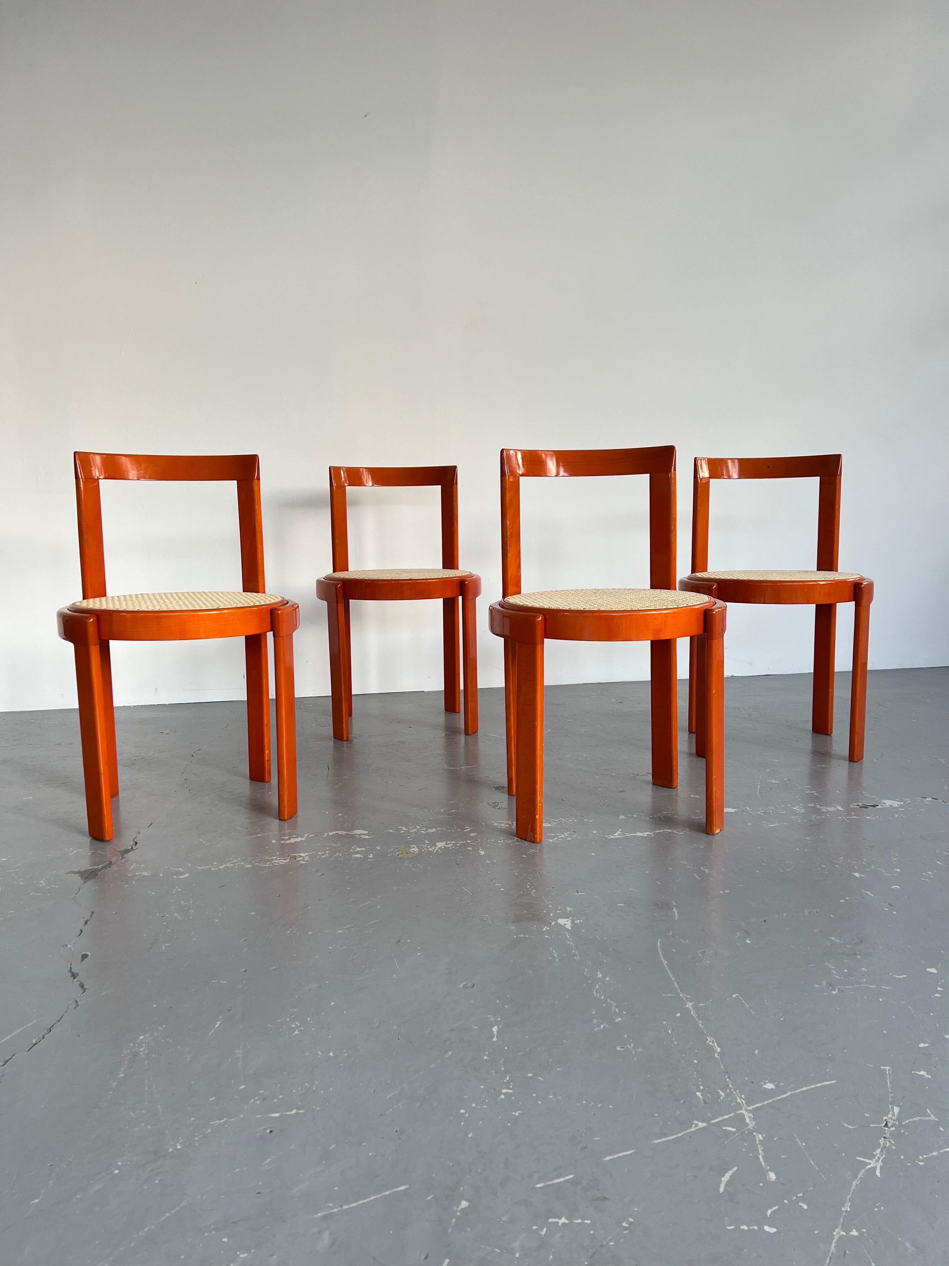 Set of four, Italian modernist dining chairs feature circular, orange stained beech frames with natural caned seats.

A rare and striking post modern dining set, with the “Made In Italy” sticker underneath, the style is very similar to the