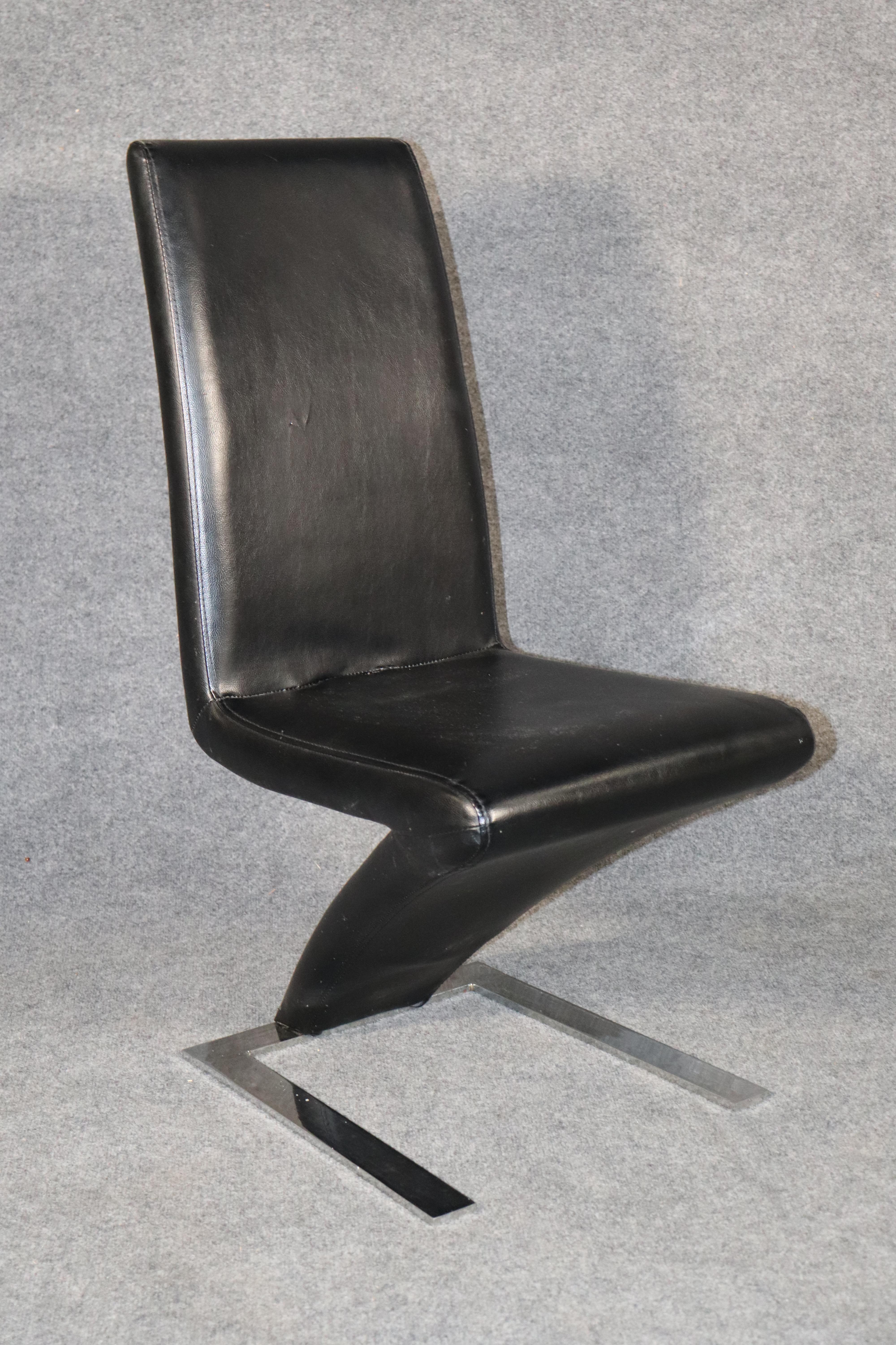Modern dining chairs with a Z shape leather seat, set on chrome metal base.
Please confirm location.
