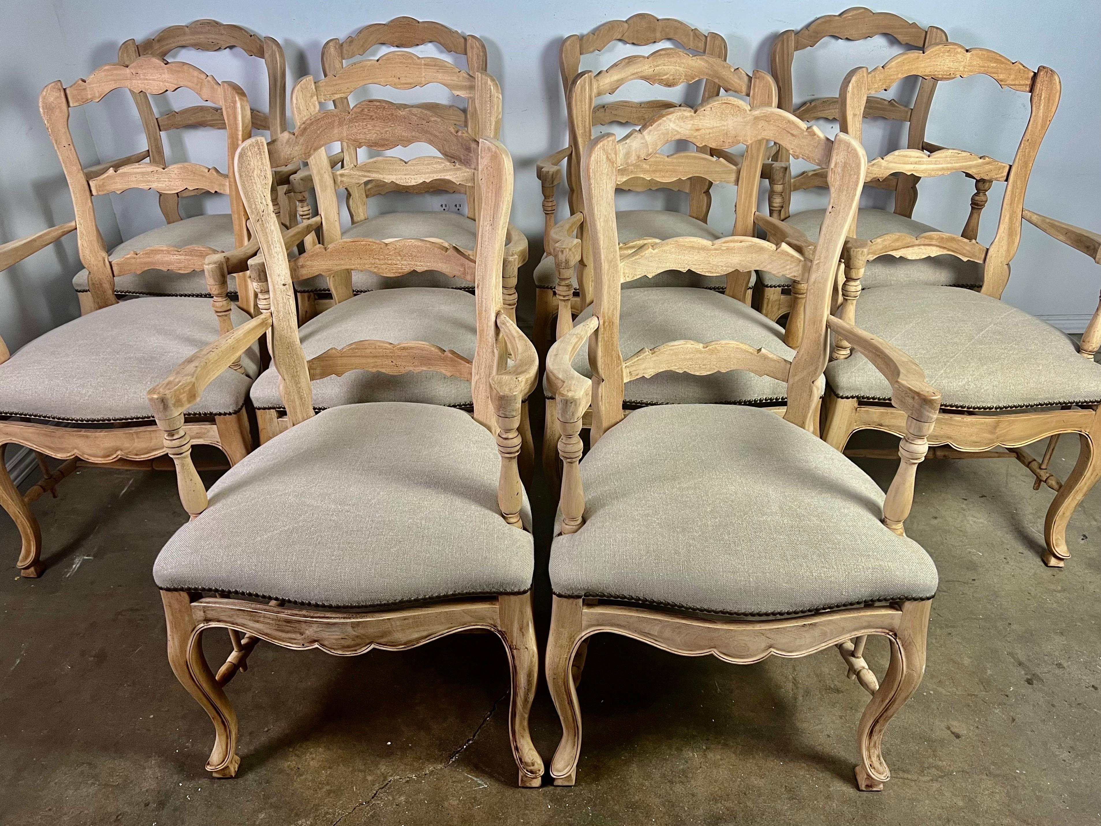 Set of (10) French Provincial style dining ladder back armchairs.  The chairs have a light natural walnut finish.  The chairs are newly reupholstered in a washed Belgium linen and detailed with nailheads.  