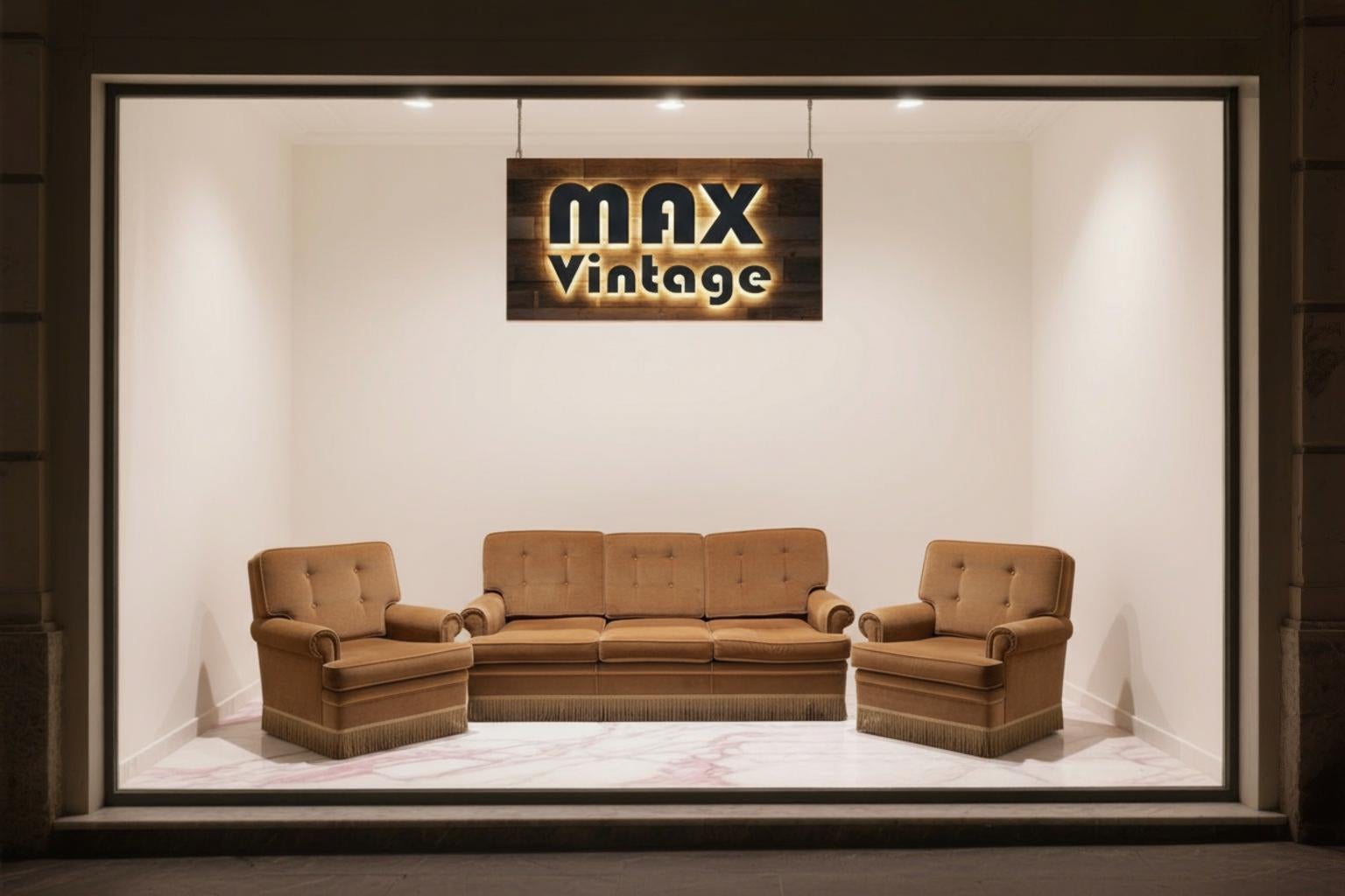 Elegante juego de salón de los años 70, compuesto por un sofá de tres plazas y dos sillones a juego. Todo el conjunto está tapizado en suave chenilla de terciopelo color caramelo, un tejido cálido y refinado que confiere a la habitación un ambiente