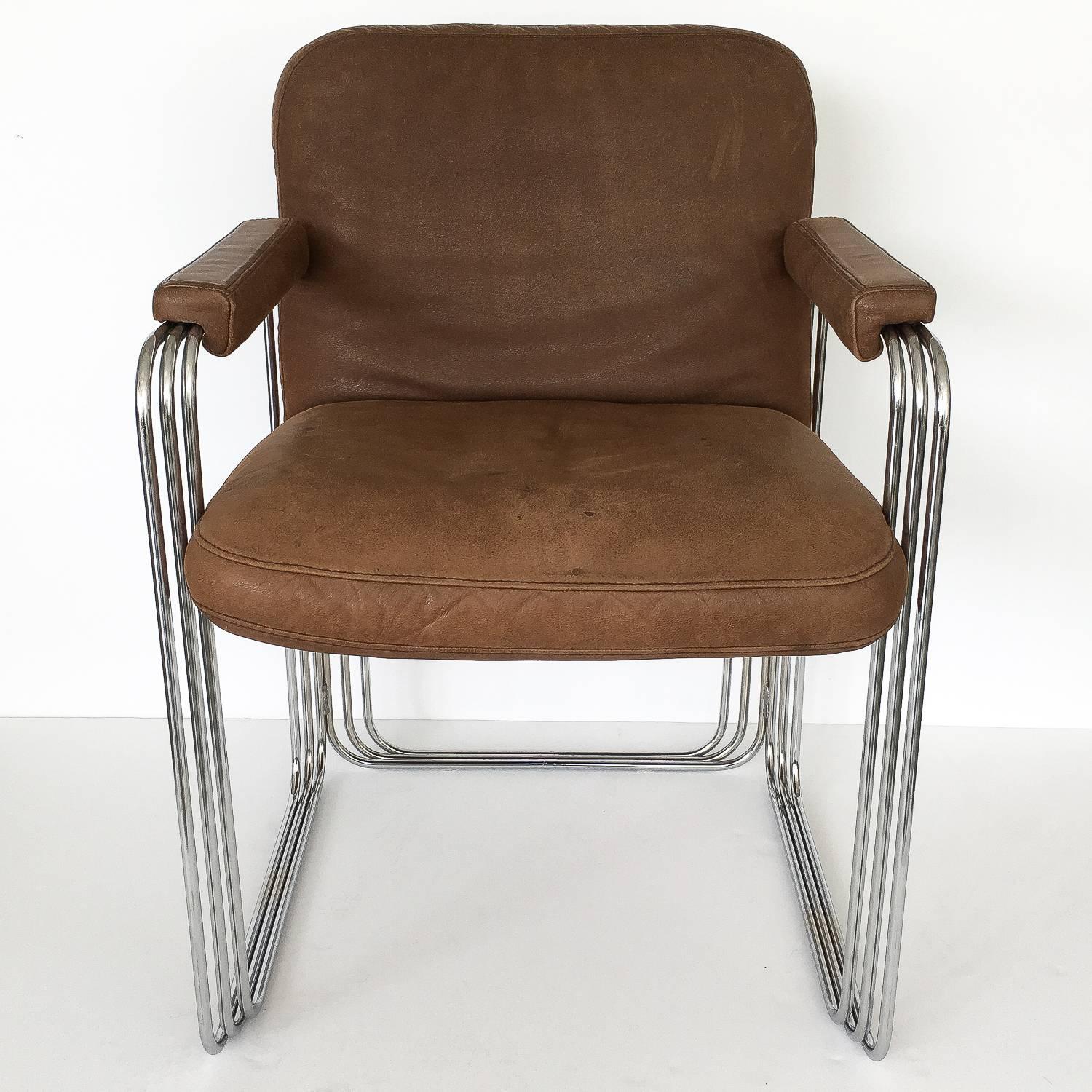 Set of six unique chrome frame and brown leather dining armchairs, circa 1970s. These chairs feature a stacked and stepped chrome plated steel sculptural frame. The frame of the chairs creates a three dimensional cage-like rectangular frame on three