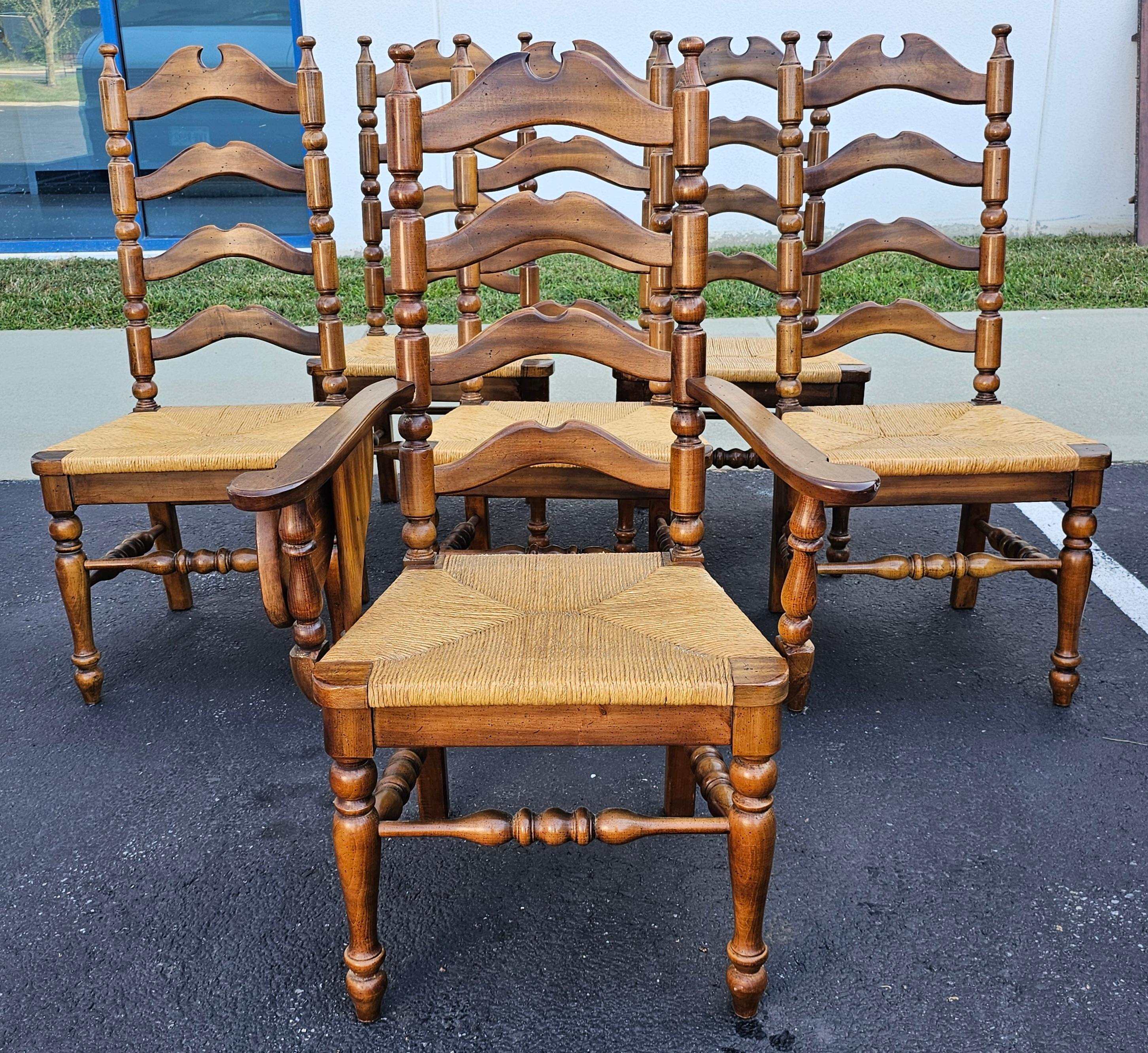 A Set of Six Early American Style Walnut and Rush Seat Ladder Back Dining Chairs. 5 side chairs and one armchair. High ladder back chairs. Chairs finish in great condition. Only rear seat of armchair has light tears on rush as pictured.
Measures