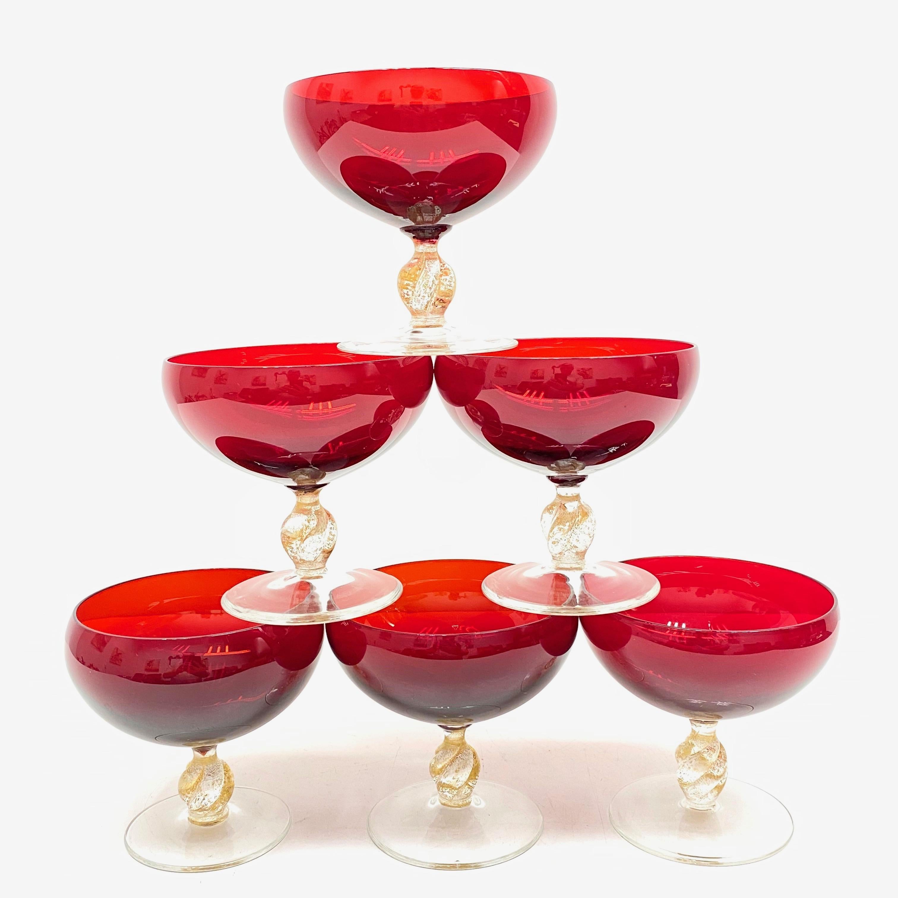 Beautiful Murano hand blown Italian art glass set of six Champagne Goblets or finger food bowls. Attributed to Barovier Toso, a Murano glass company. Made of hand blown red glass with a clear glass and gold flake stem. A nice addition to any table.