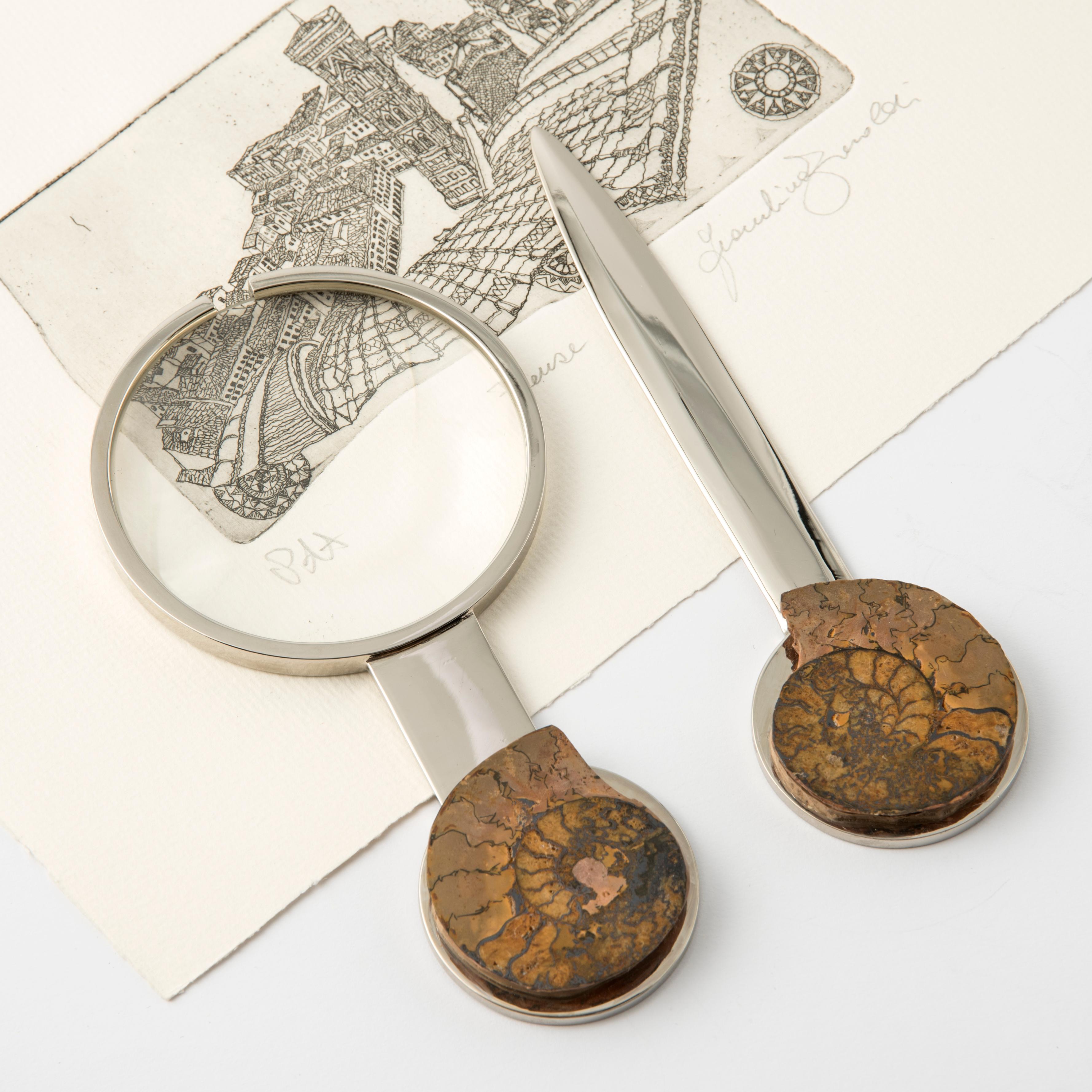 Verleihen Sie Ihrem Schreibtisch einen Hauch von Eleganz und Geschichte mit diesem exquisiten Set, bestehend aus einer Lupe und einem Brieföffner, die mit echten fossilen Ammoniten aus dem Mesozoikum verziert sind. 
Jeder Griff ist einzigartig und