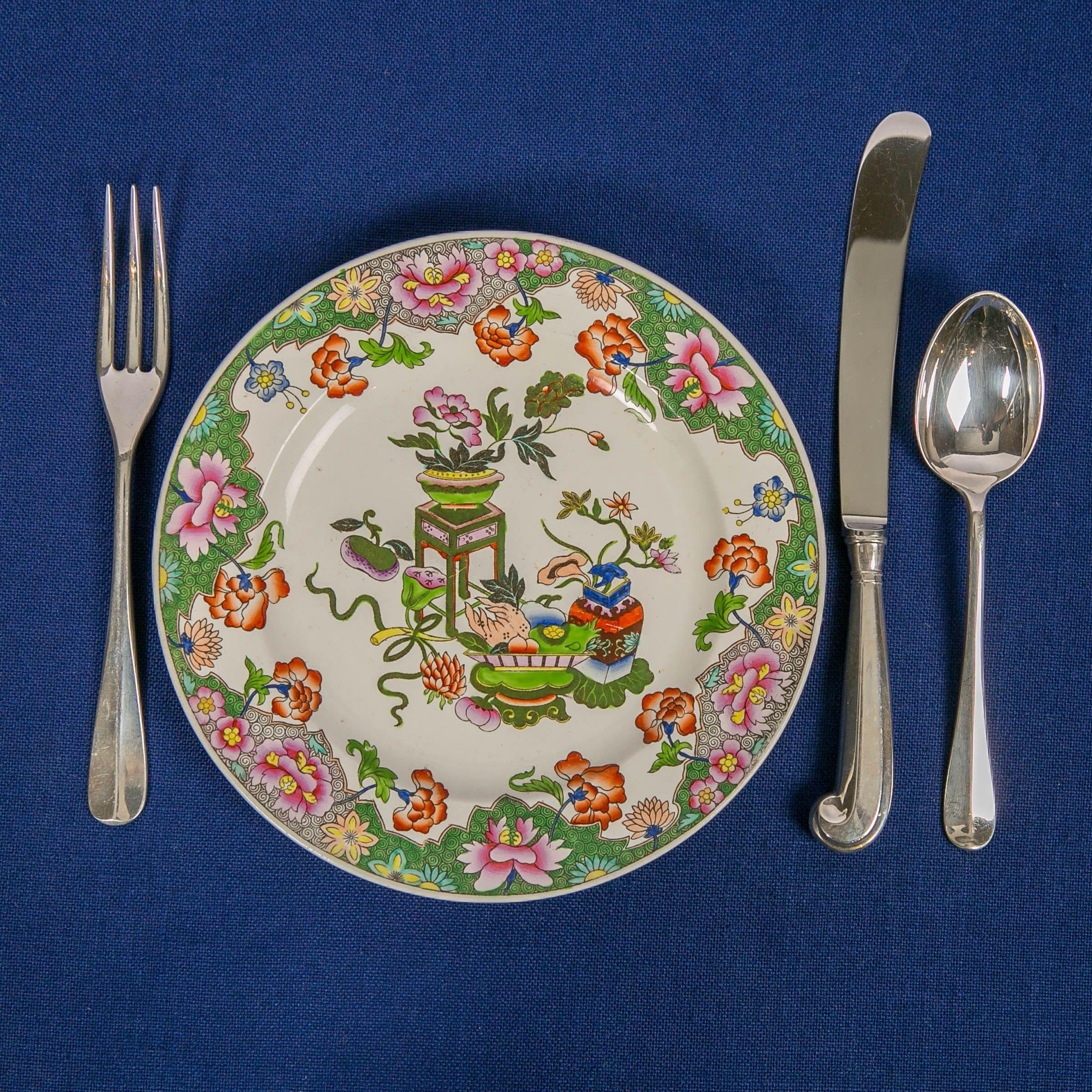 A set of ten English pearl-glazed creamware plates with chinoiserie decoration. The plates show beautiful flowers and traditional Chinese objects of good luck. Made by Spode in England circa 1820, the decoration is exuberant and asymmetrical, with a