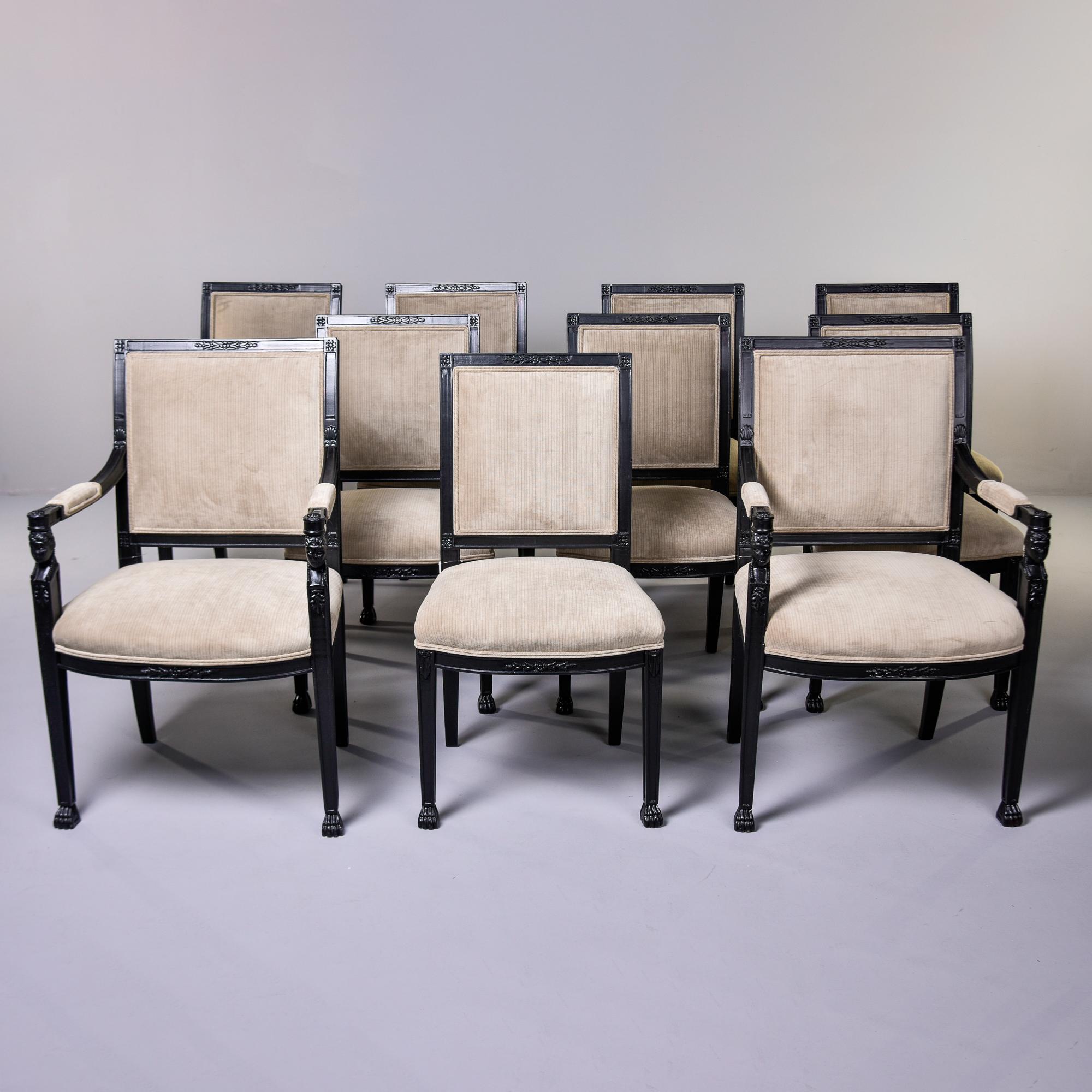 Found in the United States, this set of 10 dining chairs date from the 1980s. The set consists of two captain or armchairs and eight armless side chairs. Neoclassical style frames have a black painted finish. Armchairs feature carved figural
