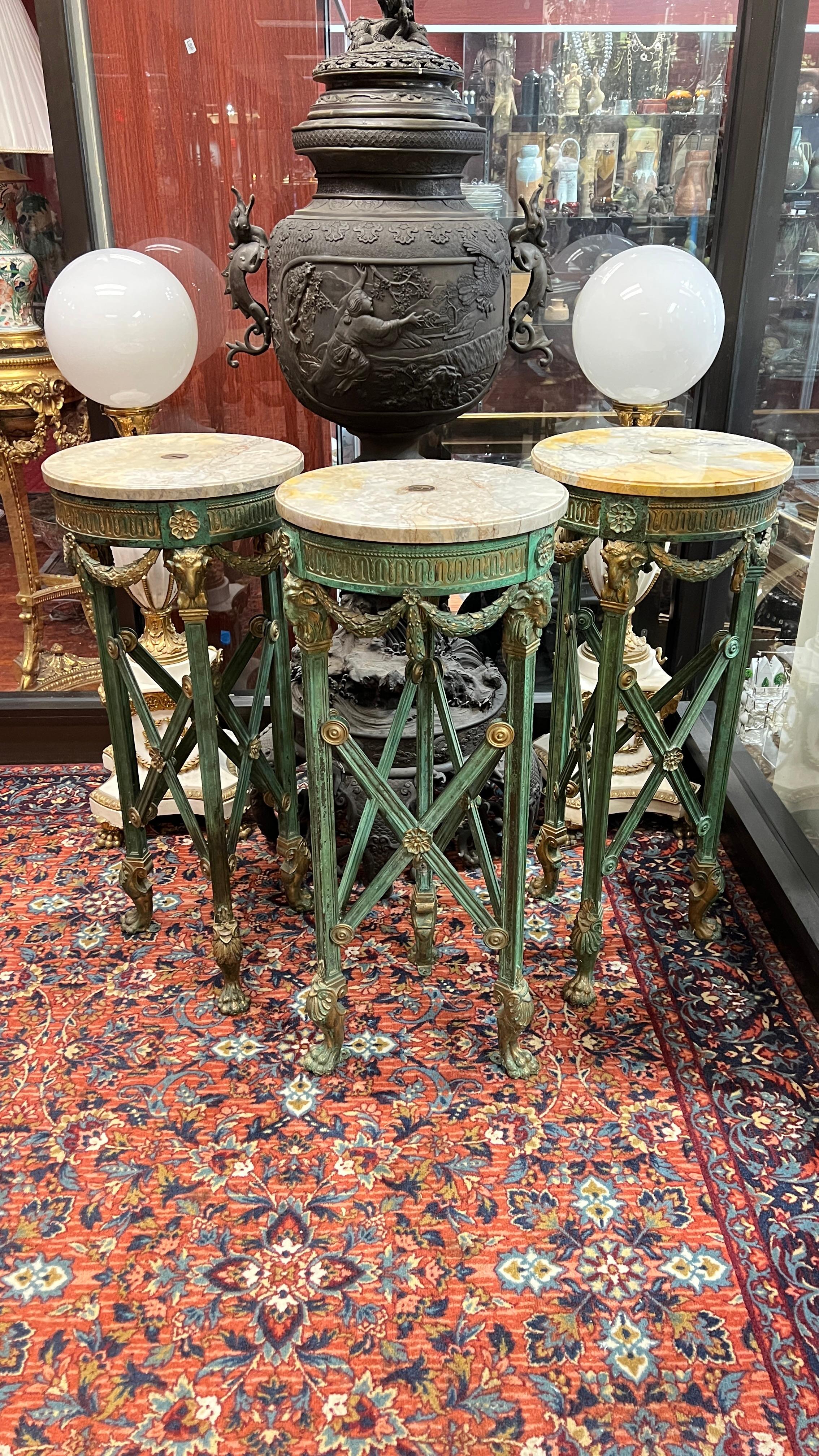 Juego de tres grandes  calidad muy fina y rara  Pedestales estilo Directoire francés  o jardineras con pátina verdigris y dorada, con encimeras circulares de mármol.  Finamente moldeado y fundido con motivos neoclásicos que incluyen patas de trípode