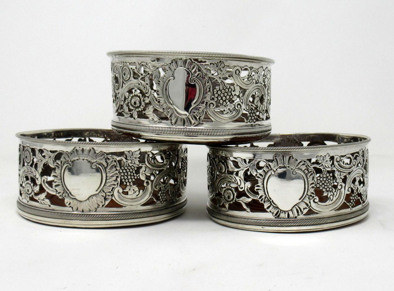 An absolutely stunning set of three Georgian style sterling silver bottler or wine coaster of exceptional quality and unusually heavy gauge silver. 

Each of traditional circular form with rope edge banded rim above lavish pierced and chased body