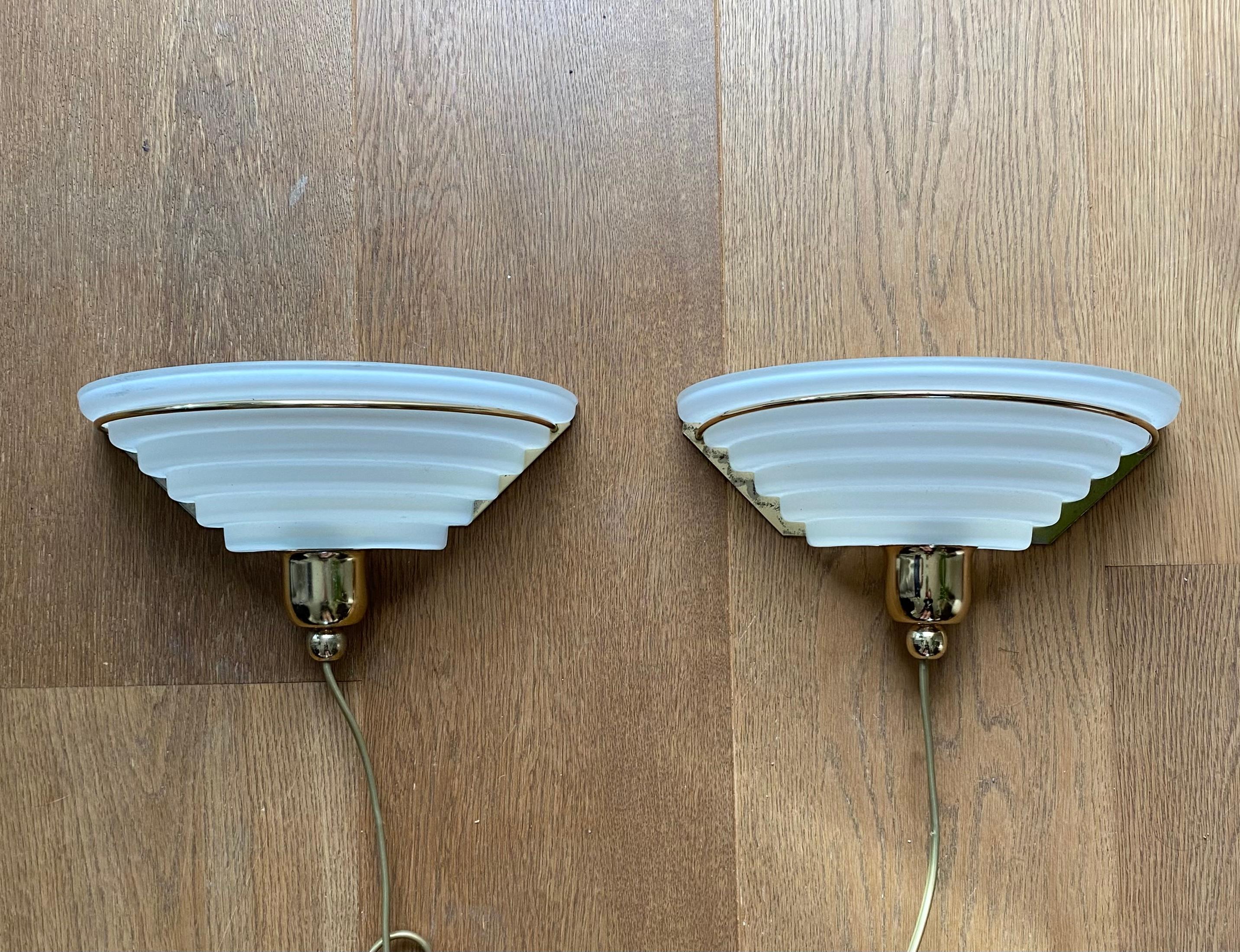 Set of two Post-Modern wall lights, sconces, in typical Memphis style. The pieces were manufactured by Lakro Amstelveen, The Netherlands in the ca. 1980s The lamps consist of a brass base and a satinated glass shade. Both lamps show some wear mostly