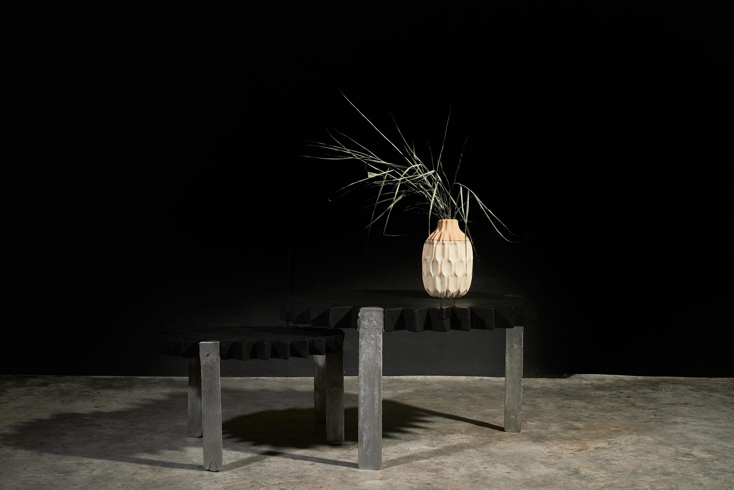 This sculptural coffee table set by Sergio Vulpe explores the raw beauty of nature and fire. Each tabletop is crafted from solid wood, hand-charred to reveal deep grain patterns and rich texture. The legs are cast in raw aluminum, unpolished and