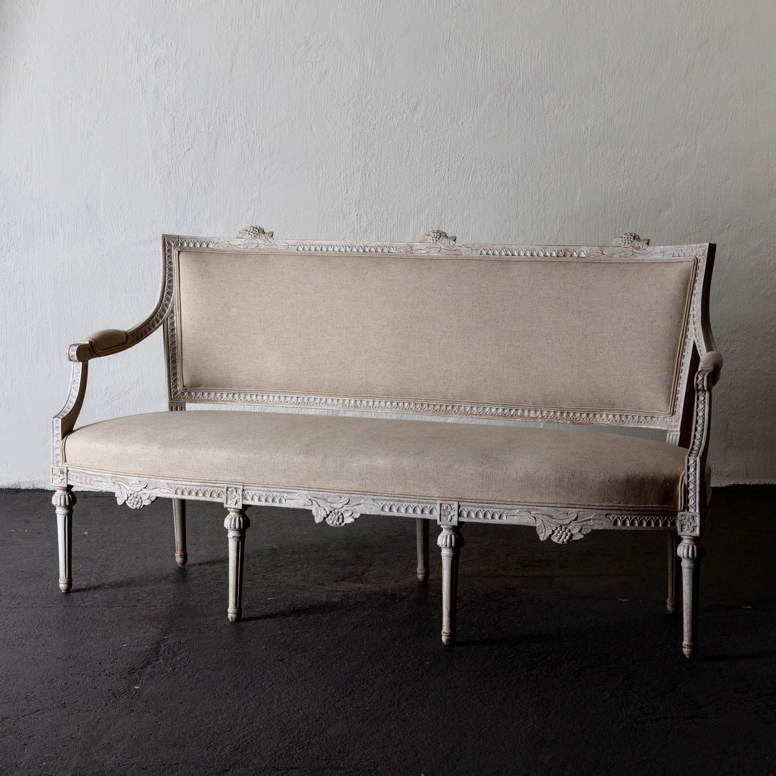 Settee bench Gustavian Swedish 19th century white Sweden. A settee bench made during the Gustavian period in Sweden. Frame in a white washed finish carved with nail tip carvings and legs rounded and channeled. Seat, back and armrests upholstered