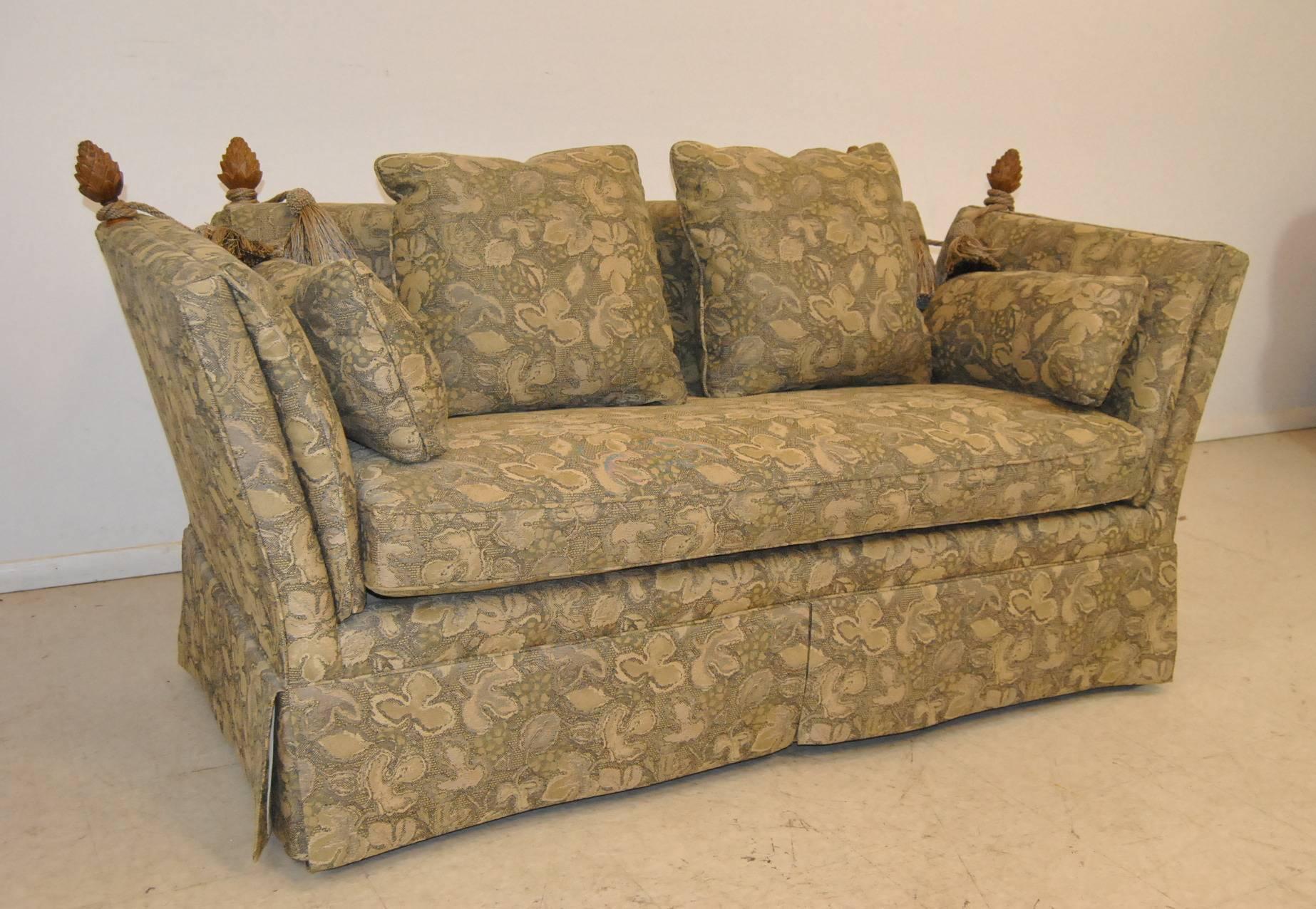 A classic knole style settee by Baker Furniture. It features carved pineapple finials and a skirted bottom. The upholstery is in great condition with no stains or wear. The pillow photo is the closest to the true color. The dimensions are 68