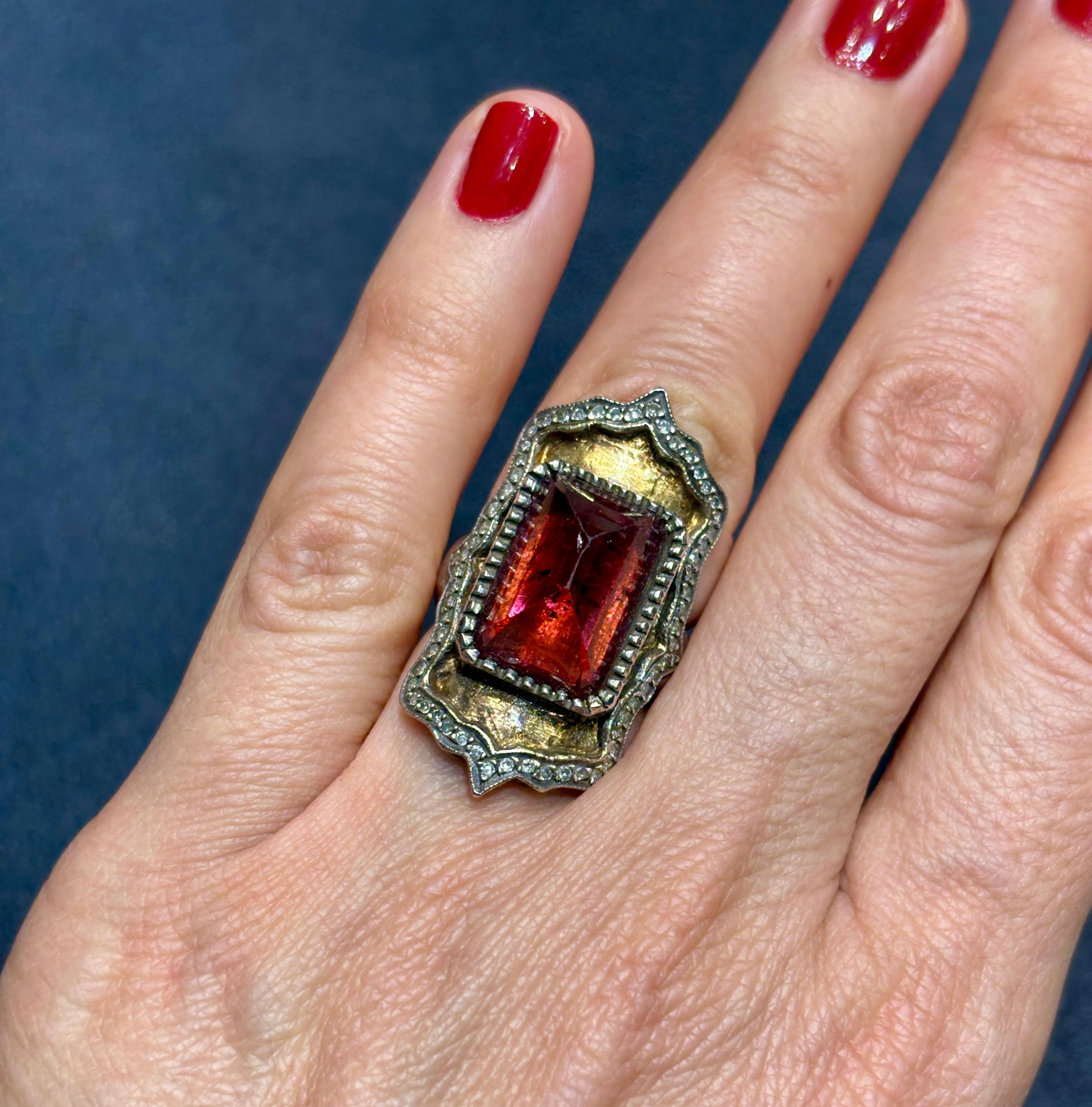 This striking cocktail ring by Sevan Bıçakç�ı is made of silver and 24k gold. The design centres around a beautiful red tourmaline that measures 11mm x 16mm. The ring is framed with  small round cut diamonds. The ring is stamped with its production