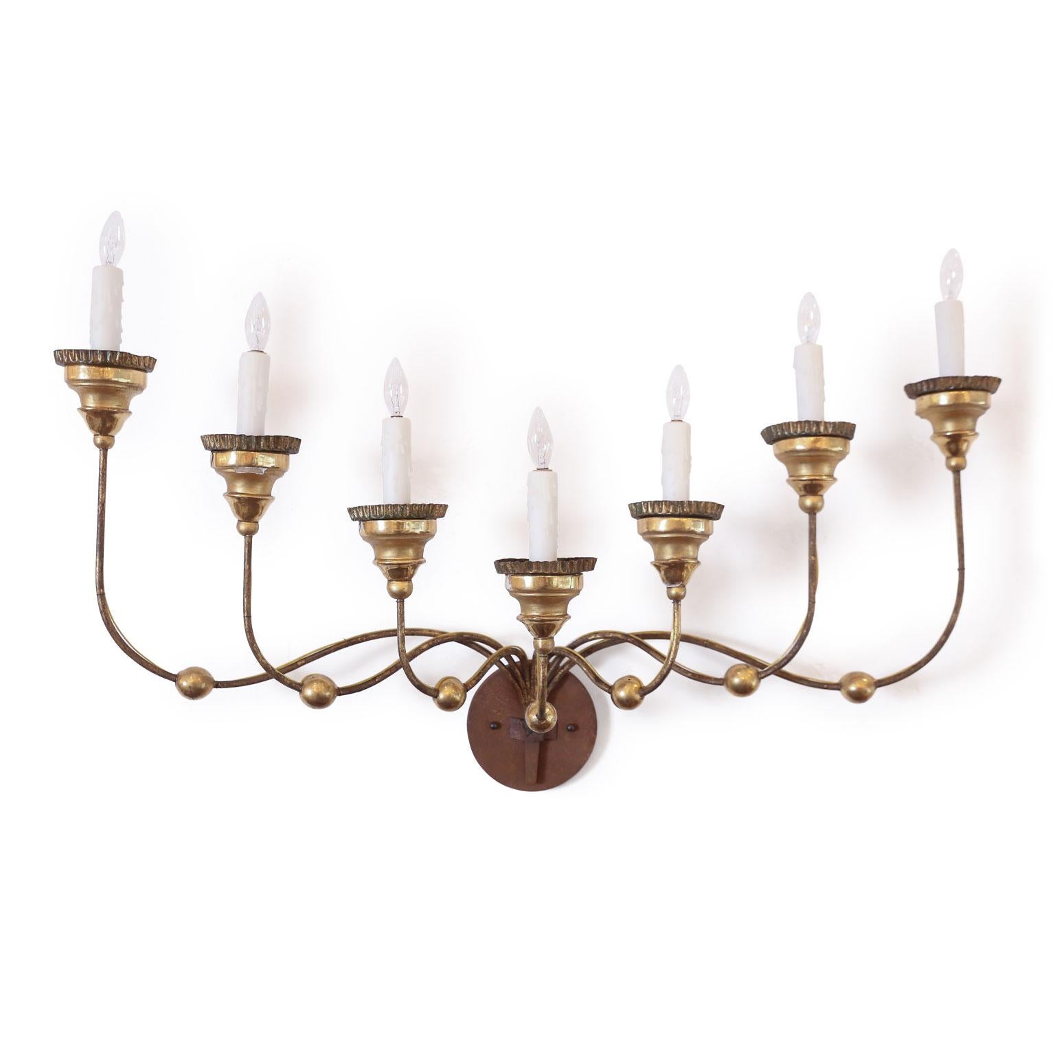Seven-arm gilt-iron sconce: arms terminate at graduated heights and are finished with giltwood bobeches and crimped-edge tole candle cups. Large-scale and dramatic. Newly-wired for use within the USA.


 