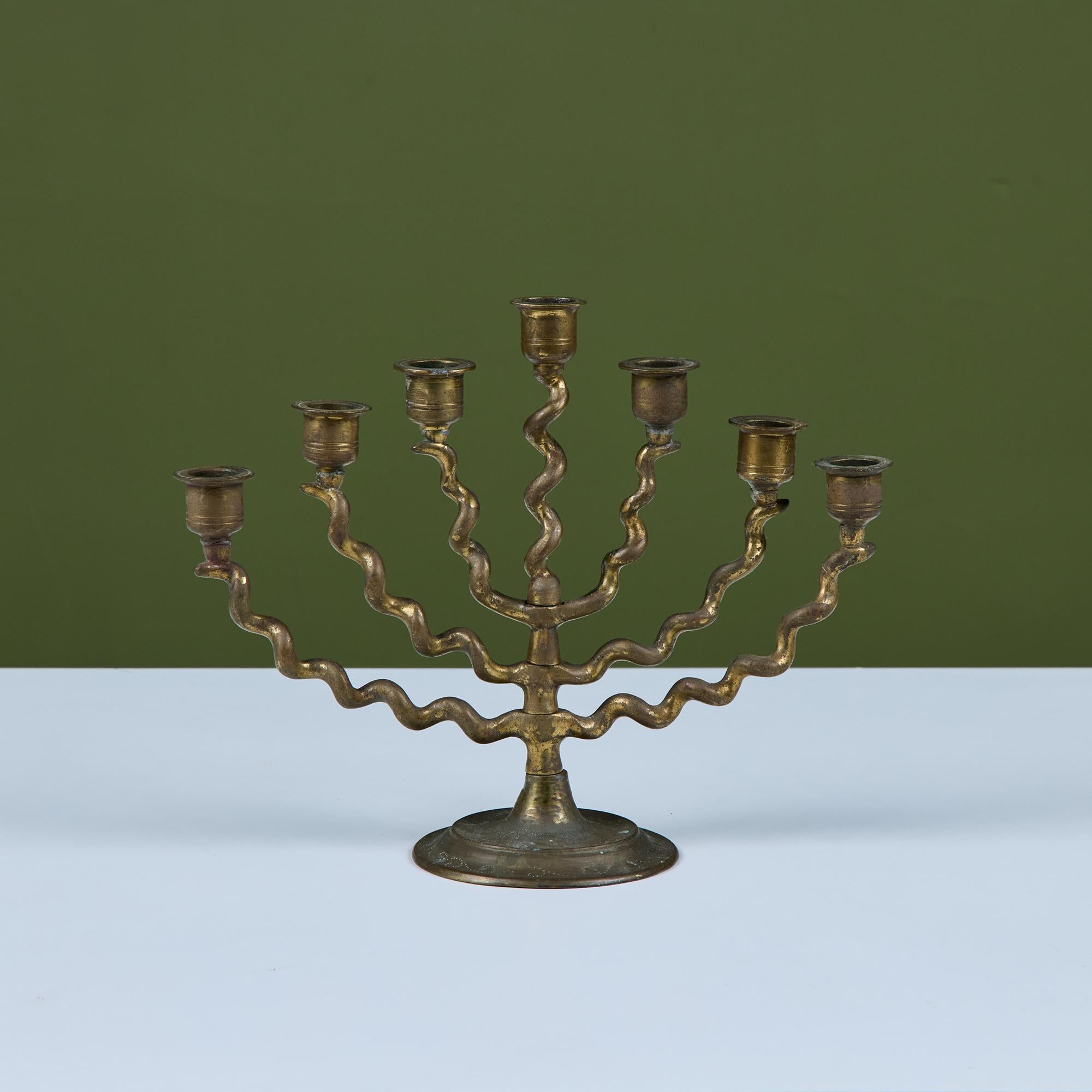Traditional seven branch brass spiral Menorah. This piece features seven branches each with a playful corkscrew arm. Signed by the artist on the underside.

Dimensions
11.5