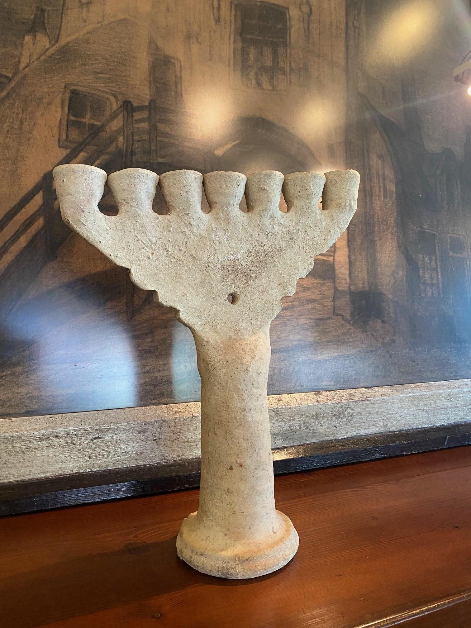 Seven candle handmade ceramic menorah or candelabra. Unglazed matte surface has a warm organic texture with natural earth tone coloring.  Pedestal base supports seven candle cups.  1970's
