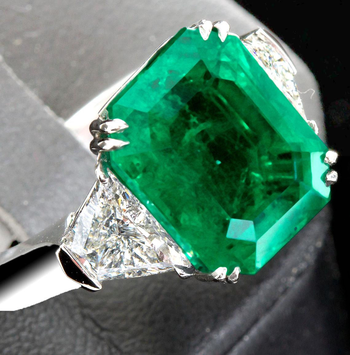 A remarkable deep transparent green 7.44 ct Colombian emerald with only minor clarity enhancement set in a platinum ring with two trapezoid shape diamonds, 1.37 ctw. Accompanied by AGL Prestige Gemstone Report.
Emerald size: 13.18 x 10.37 x 6.73