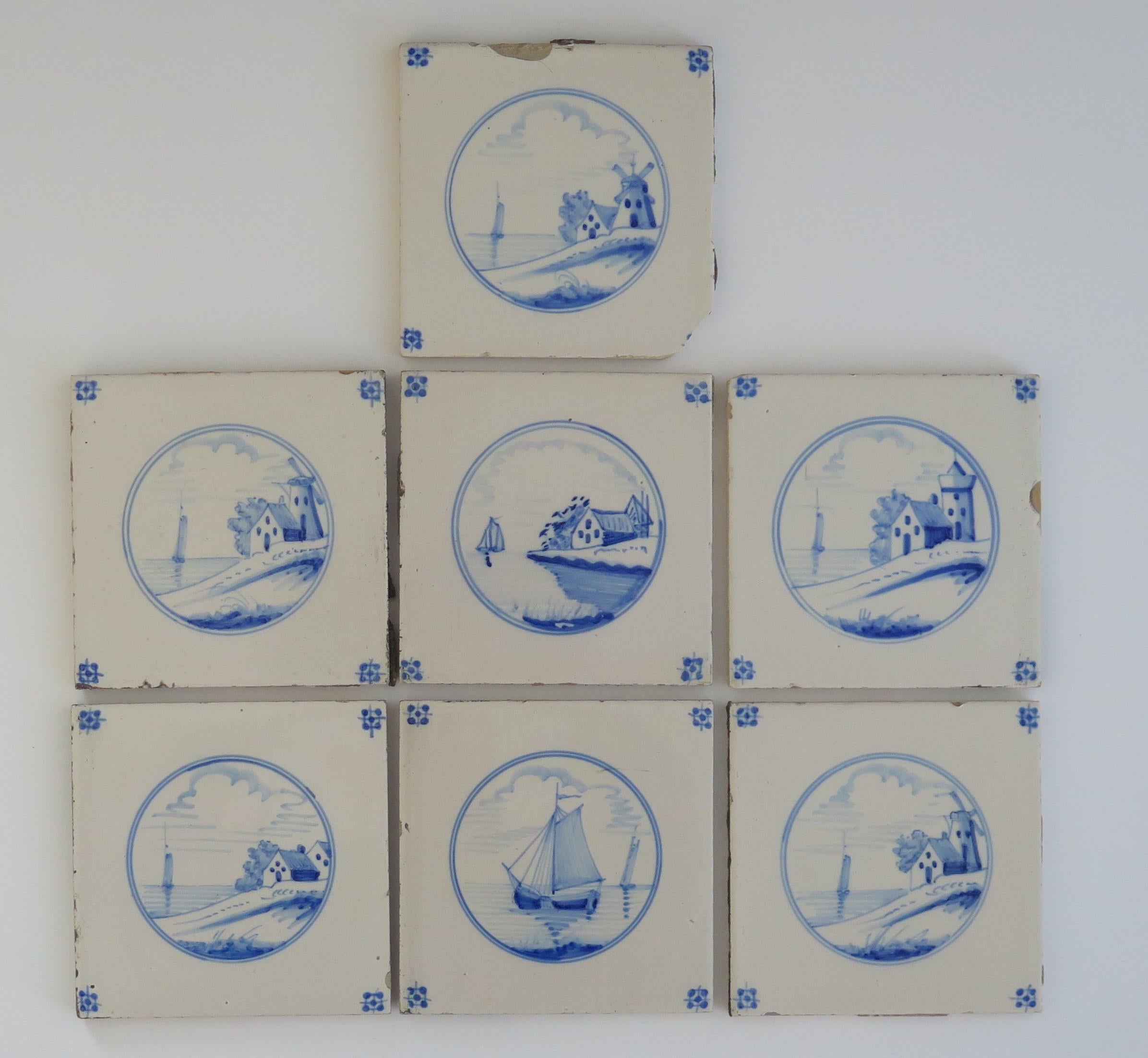 These are Seven Delft wall tiles, all with hand painted blue and white waterside landscape scenes, made in the Netherlands during the 19th century. 

The tiles are ceramic, made of earthenware and nominally about 5.2 inches square.

The set of