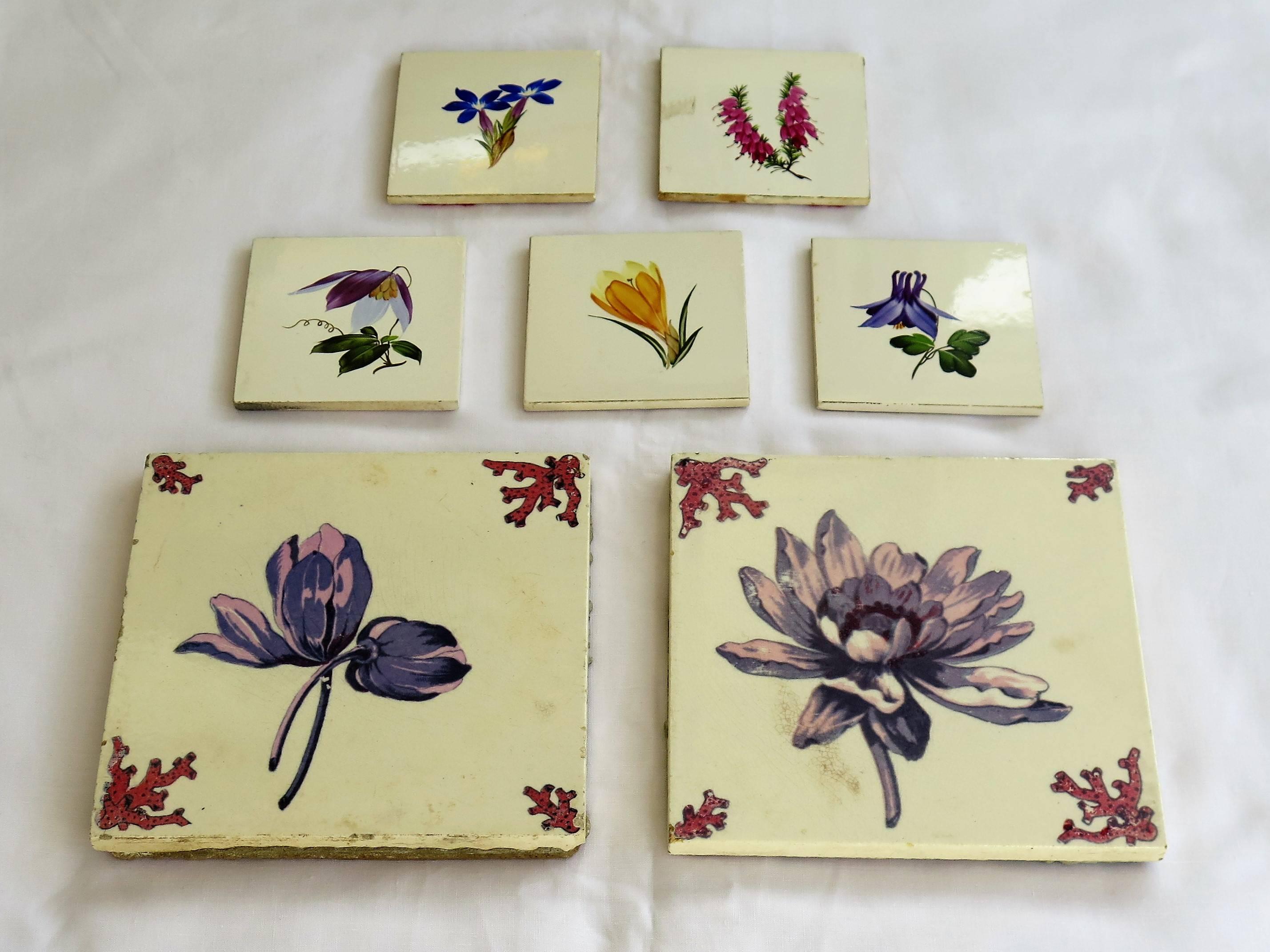 These are two sets of hand-painted ceramic wall tiles with a floral theme from the 20th century.

Set one - Two large tiles, two different flower patterns in pink and mauve shades 
 with dark pink corner motifs. Possibly from the Netherlands, circa