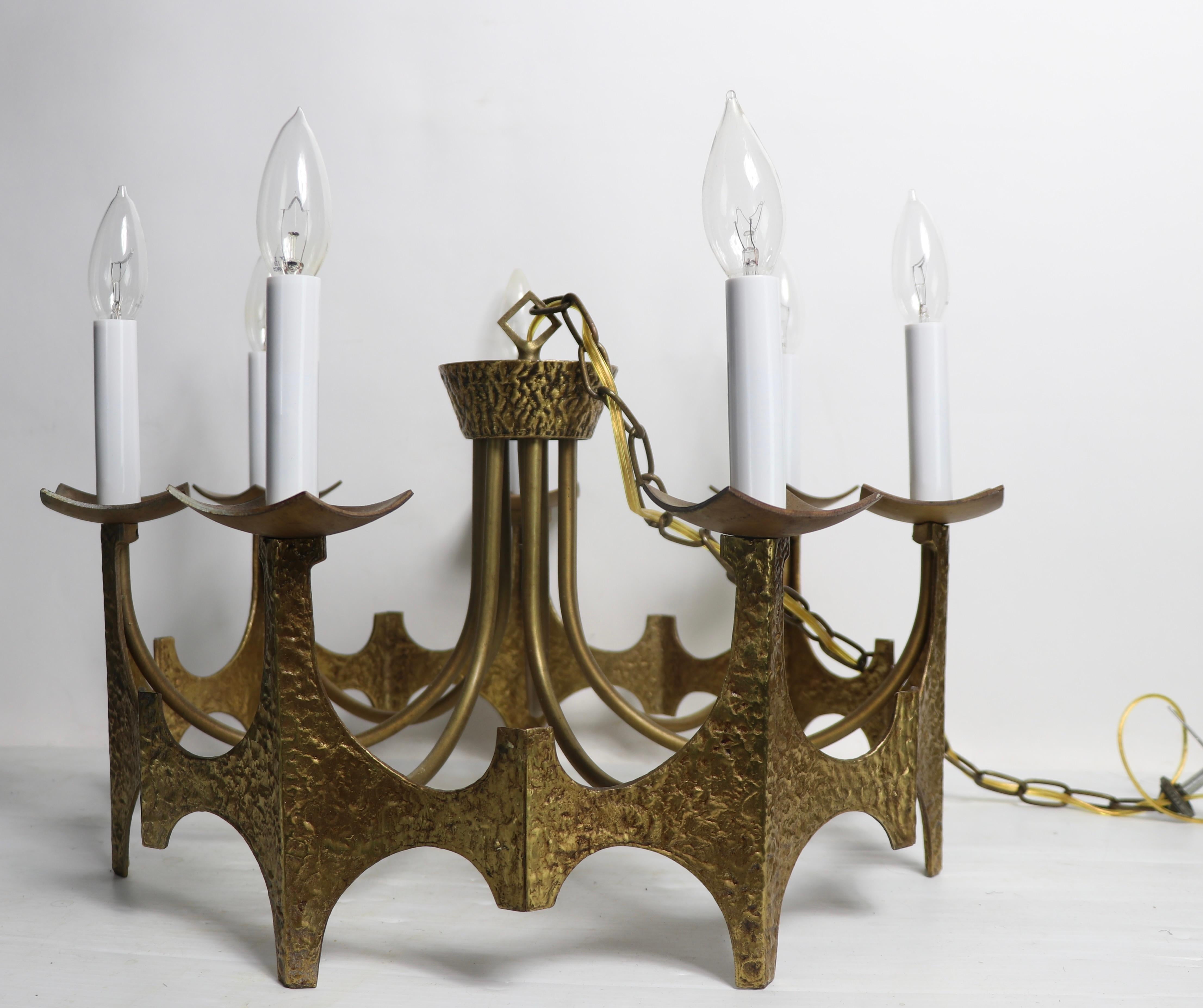 Brutalist hammered brass ring form chandelier having 7 candlestick lights. Made by noted American lighting manufacturer Moe Bridges. This example is in very good, clean and working condition, it has been newly professionally rewired. Ready to